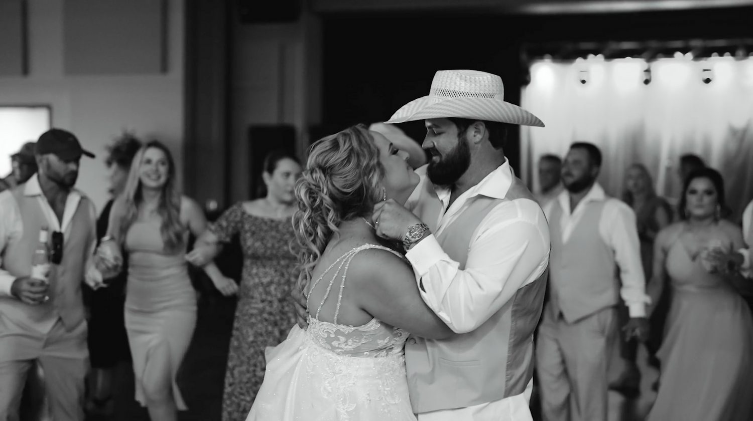 Black and white candid moment of wedding celebration in an elegant indoor venue.