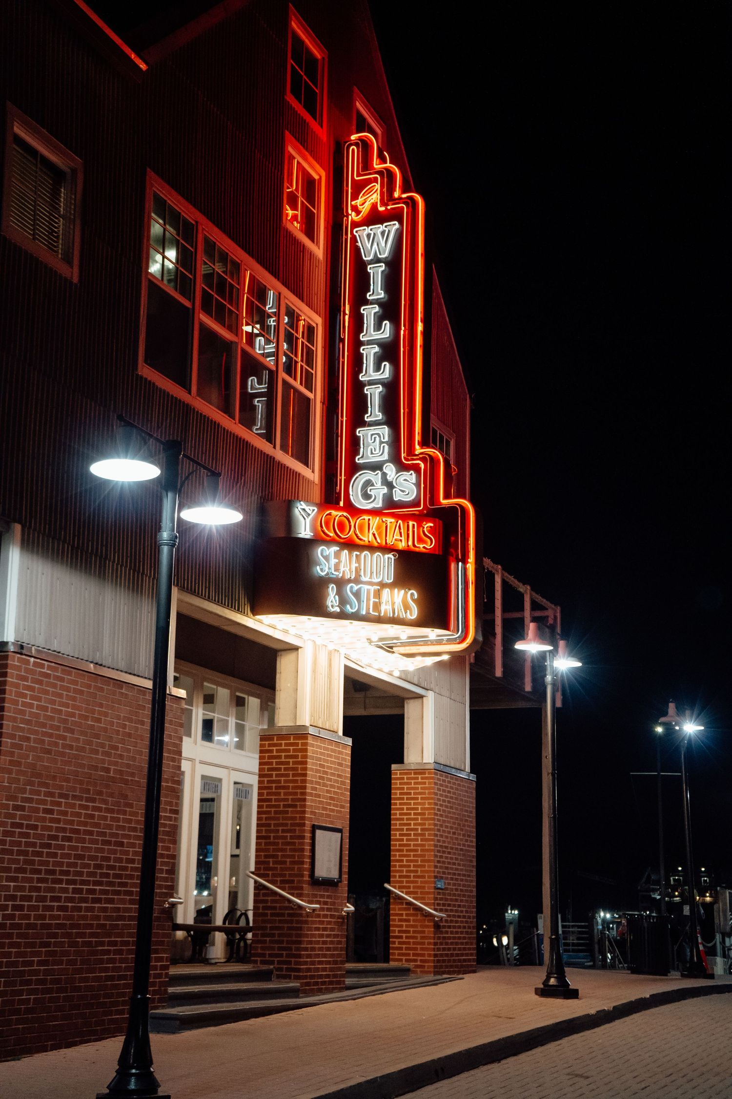 Illuminated neon signs light up the exterior of a brick building at night.