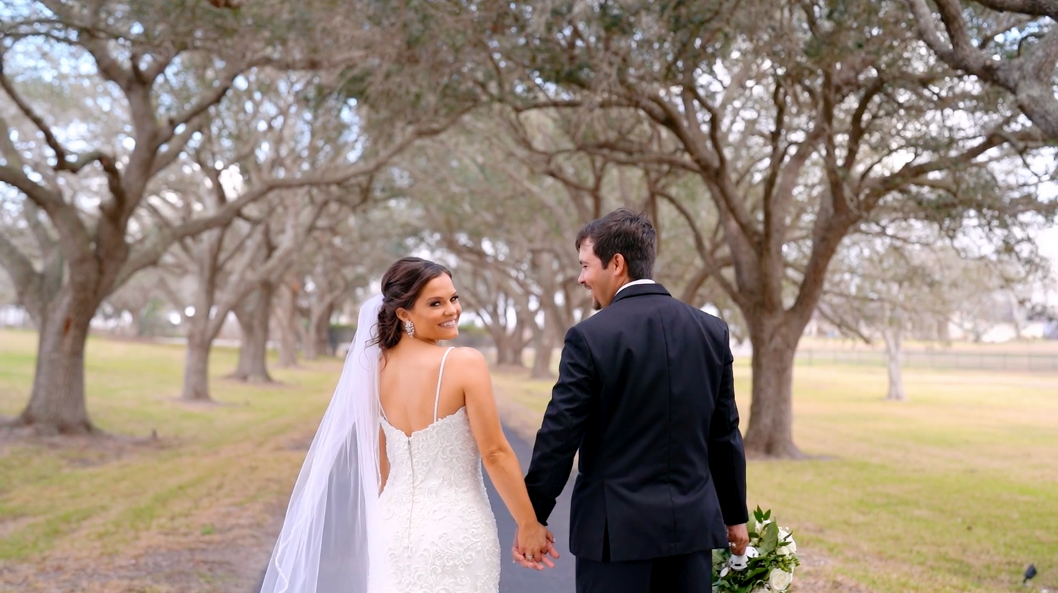 Wedding celebration scene outdoors with large oak trees creating a natural backdrop.