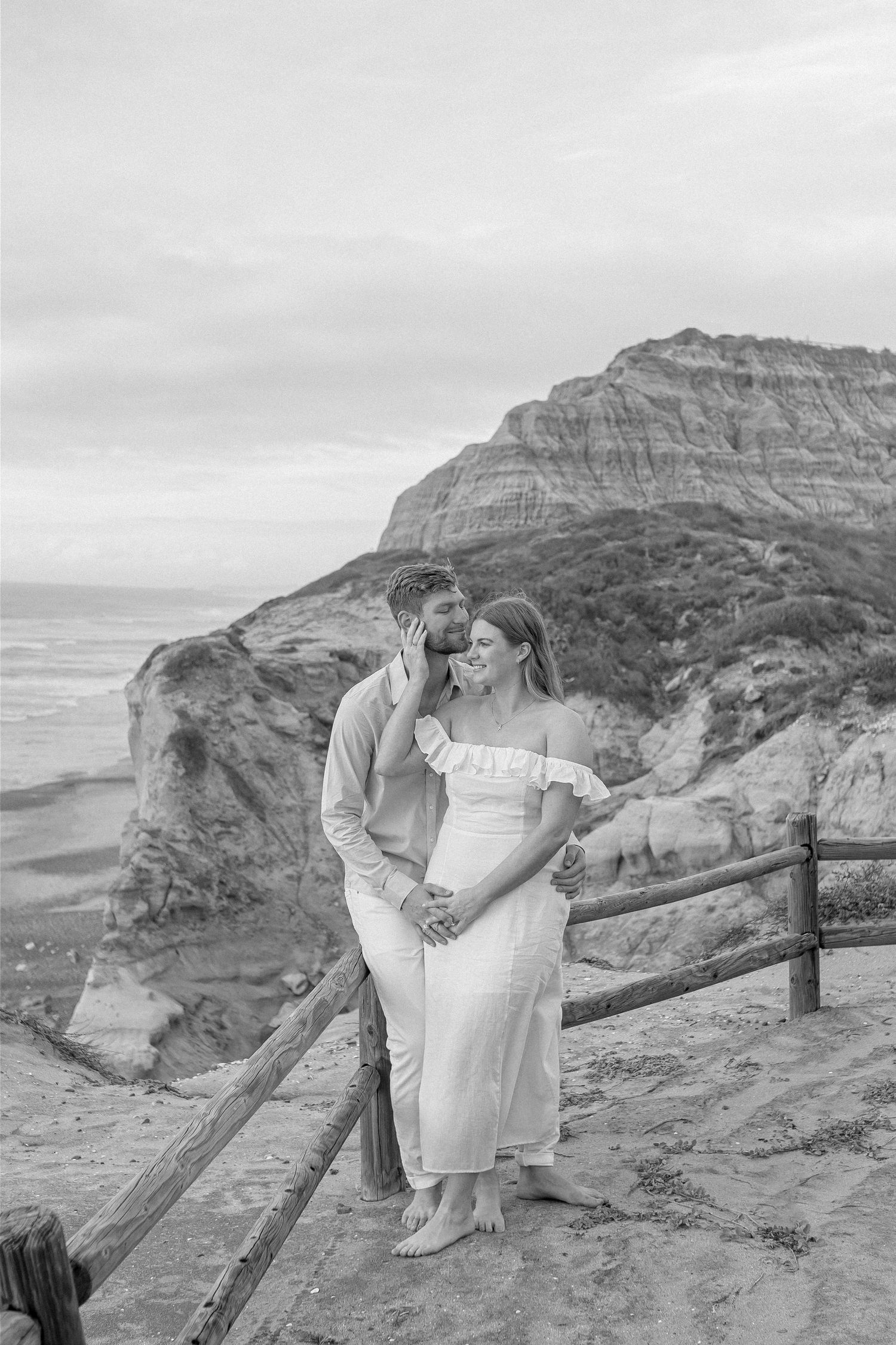 Black and white maternity photos on rocky cliffs showing intimate moments against dramatic landscape.