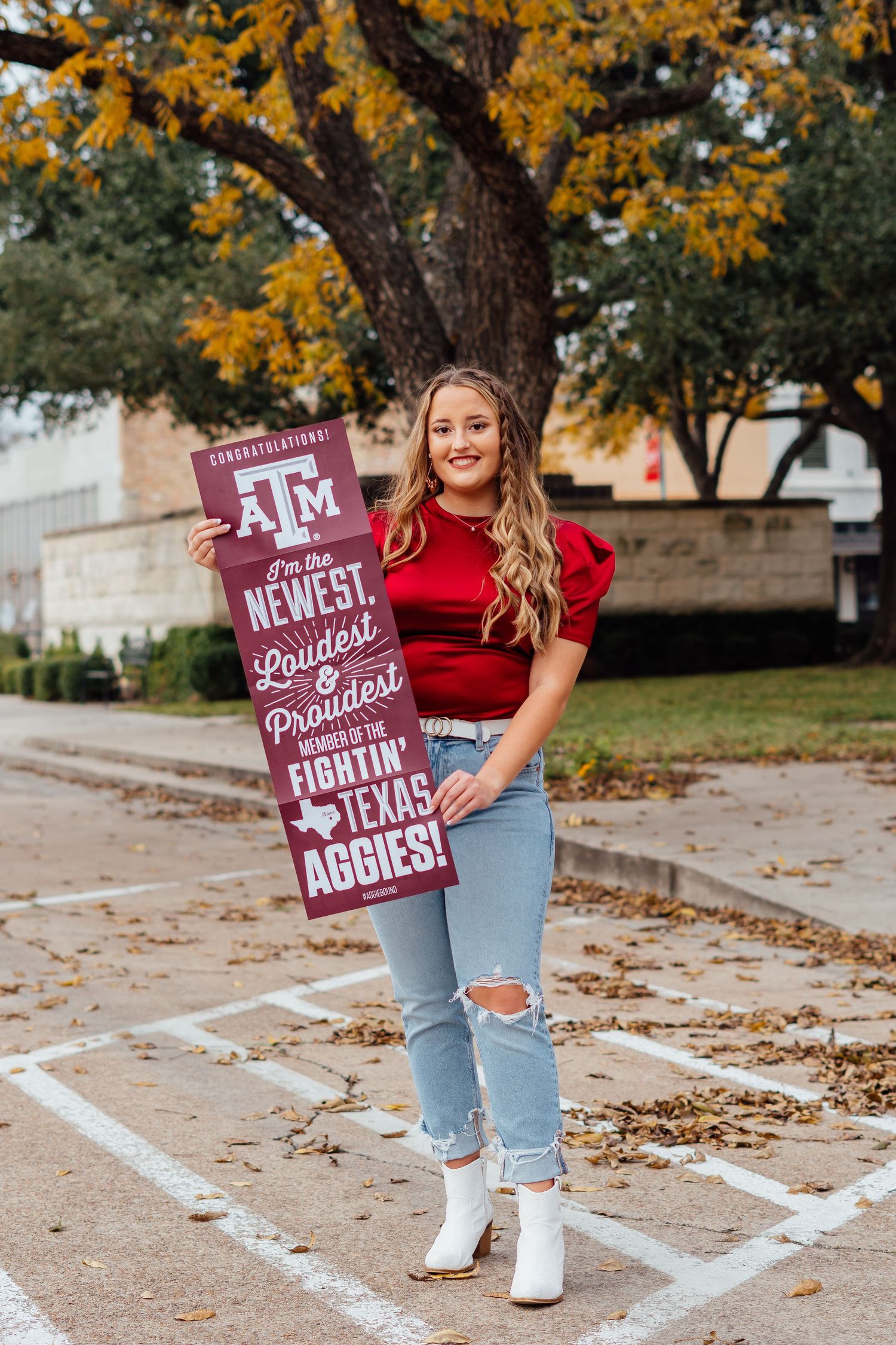 College spirit photos with Texas A&M sign wearing red top and light jeans on campus grounds.