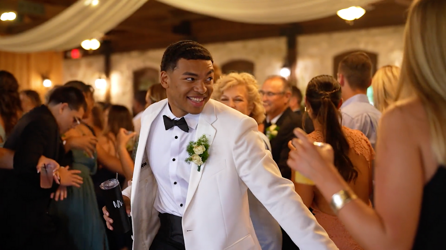 Guests dance and celebrate at an elegant wedding reception under warm lighting and draped fabric decor.