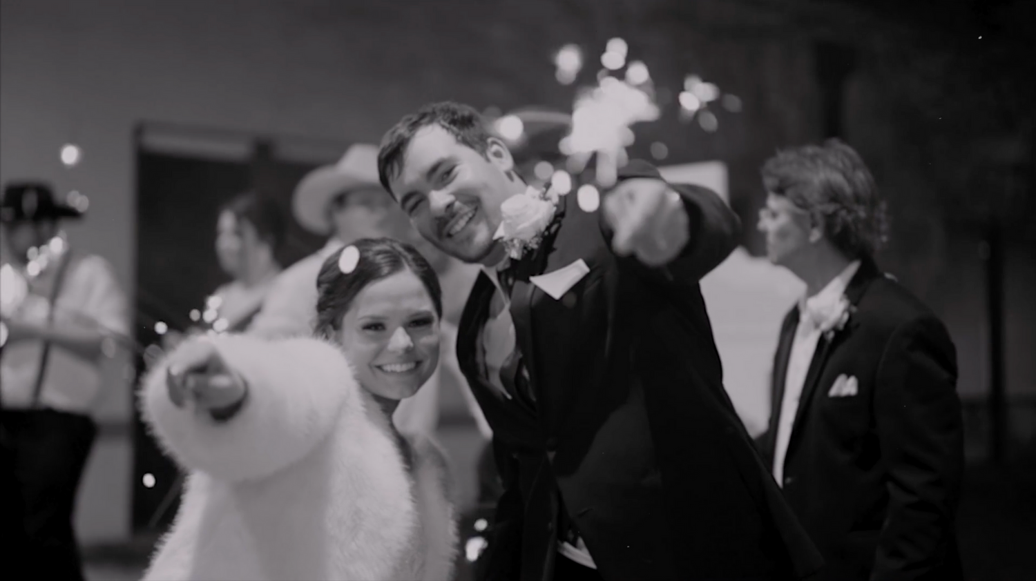 Blurred black and white image showing silhouettes of people at an event.