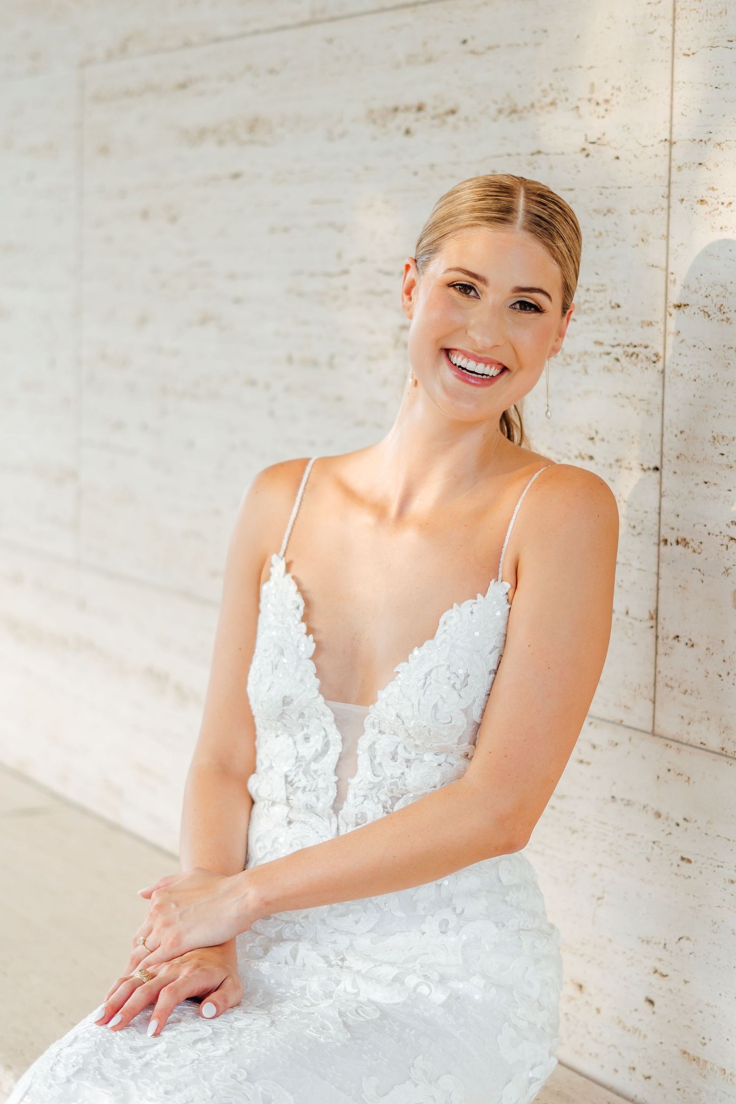 Close-up bridal portrait showing radiant smile and delicate white lace wedding dress details.