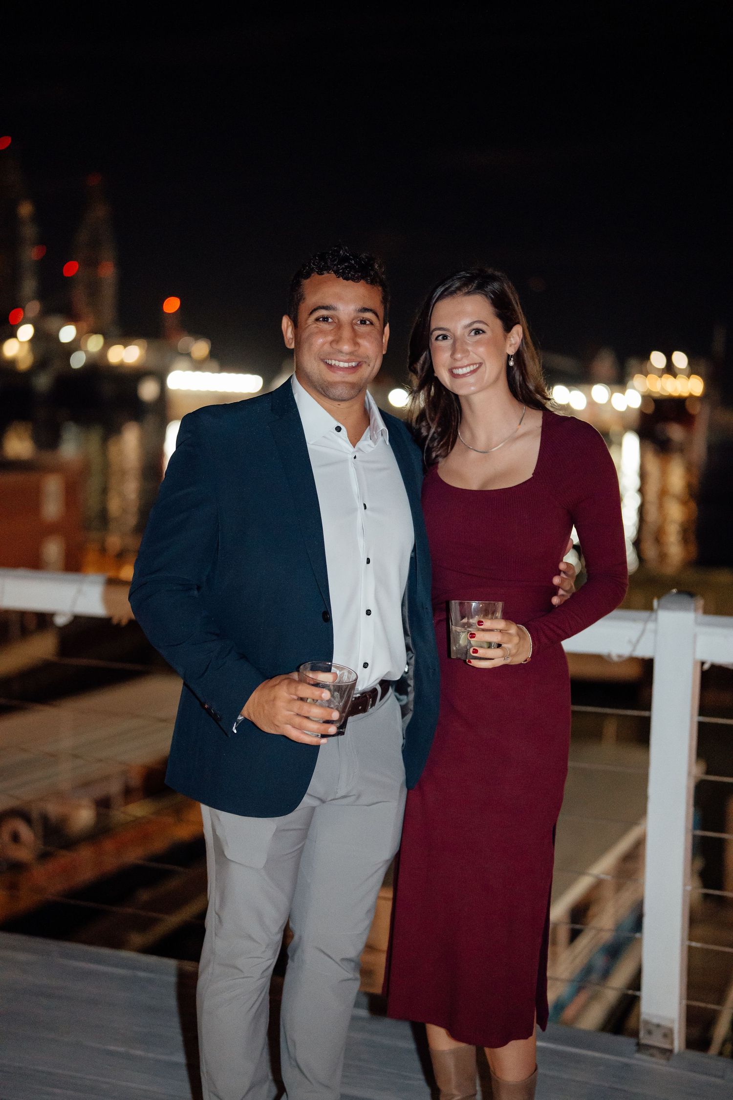 Couple enjoying drinks together at a nighttime waterfront venue.