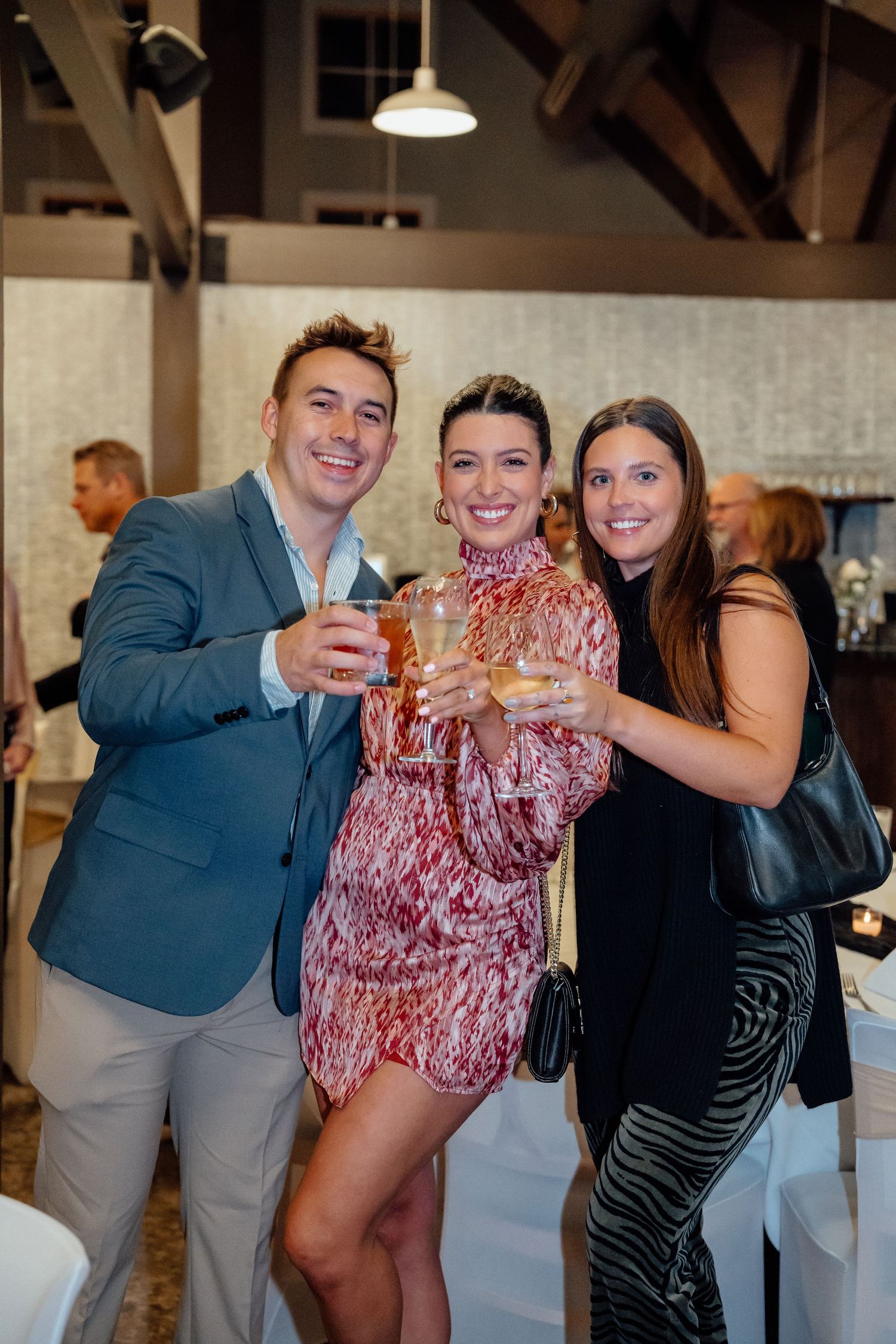 Group of guests raising glasses in a toast during an elegant indoor celebration.