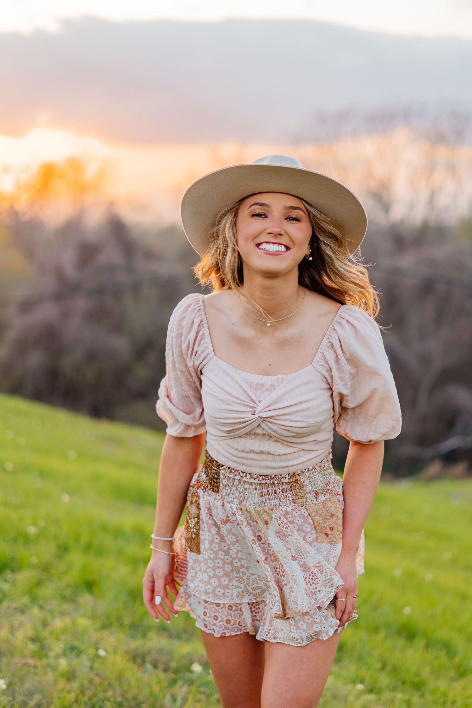 Carefree dancing in vintage-inspired outfit with straw hat during sunset photoshoot.