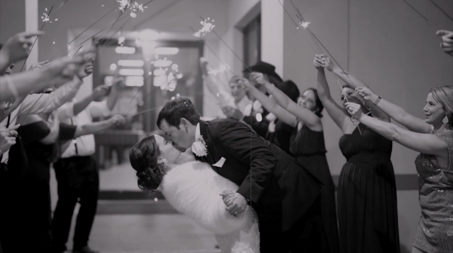 Wedding celebration candid moments in black and white with guests raising arms.