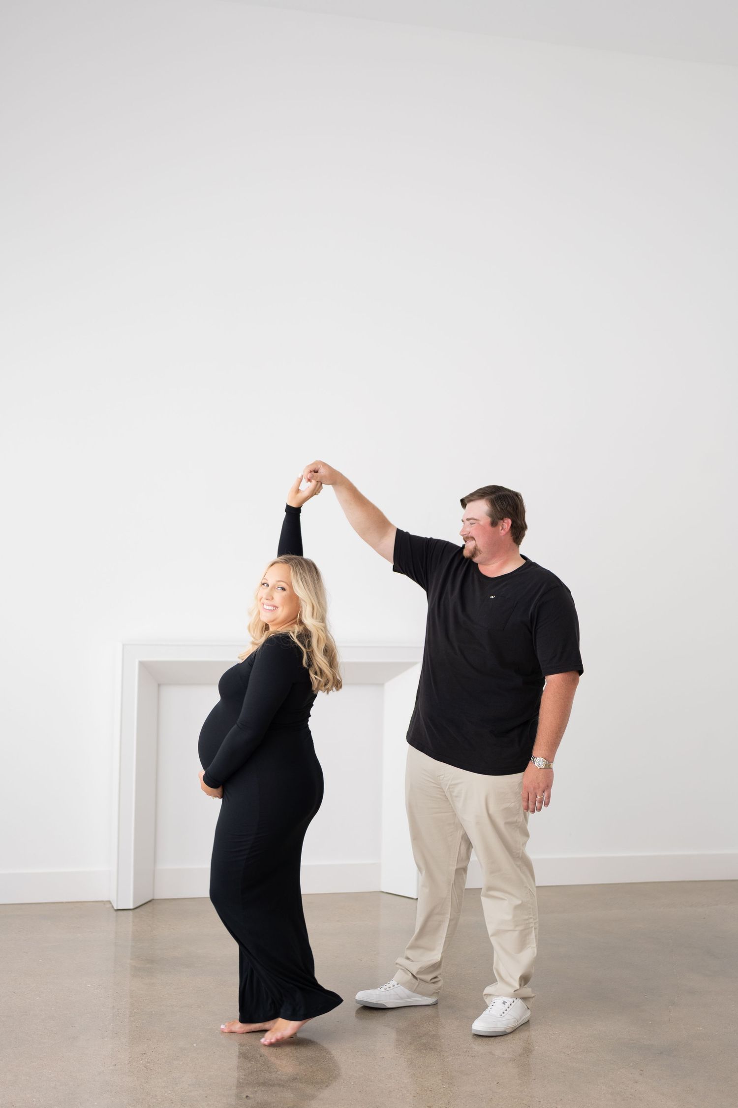 Playful maternity dance sequence against white studio backdrop.