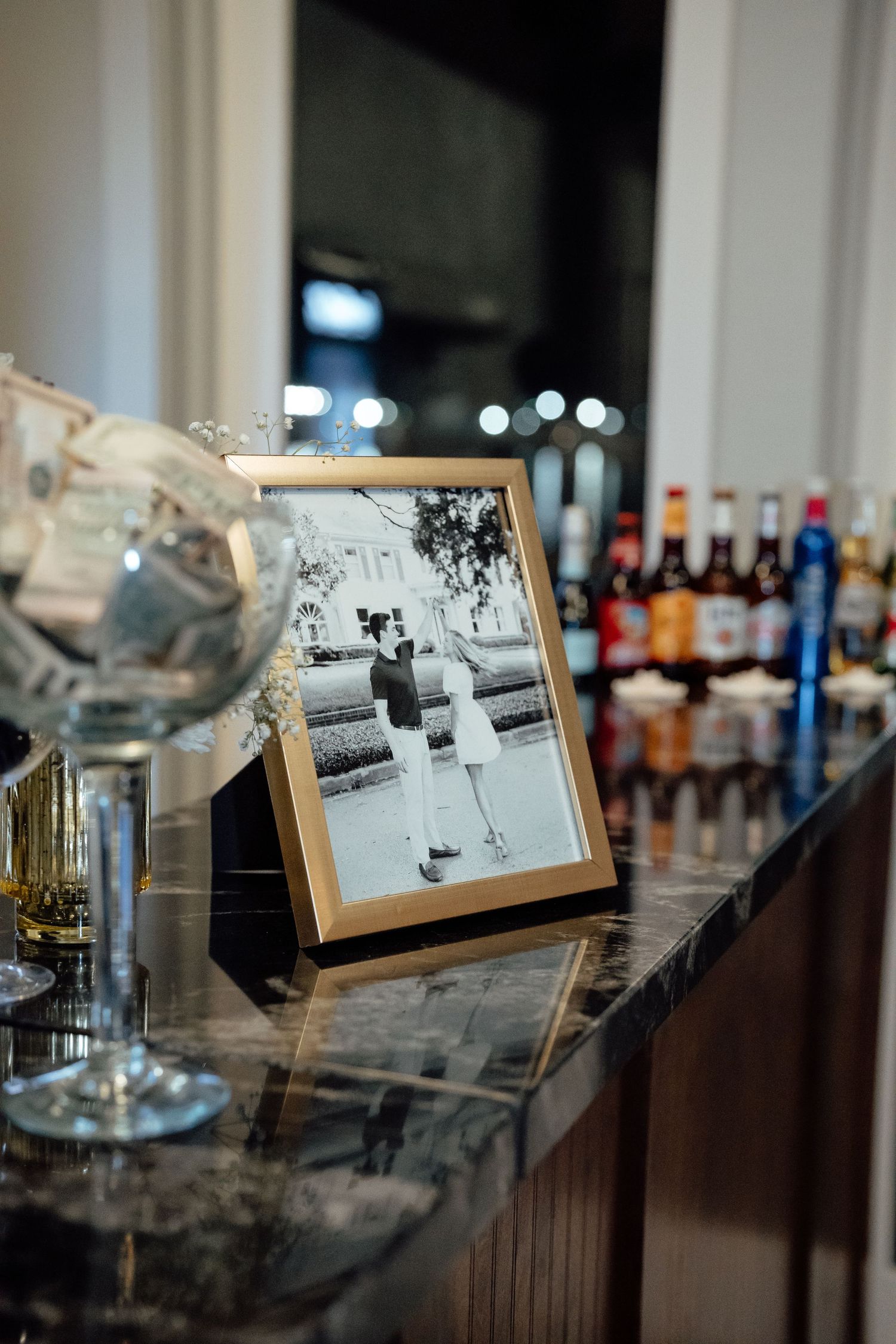 Vintage black and white photographs displayed on stands alongside wine bottles at an event.