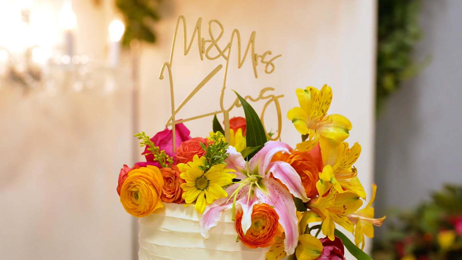 Vibrant spring flowers in yellow and orange tones decorating a wedding reception table.