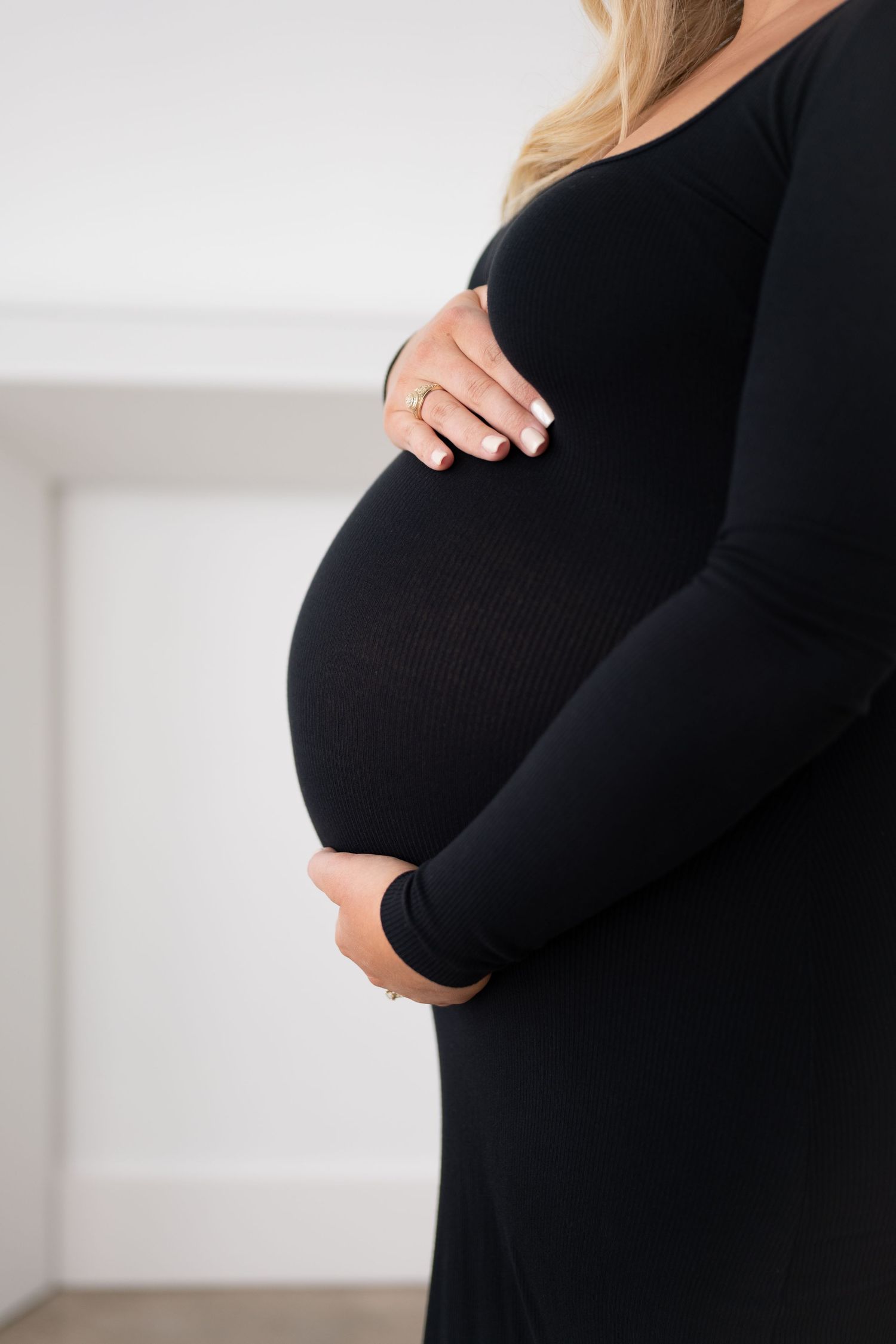 Side profile of pregnant woman in black dress showing baby bump progression.