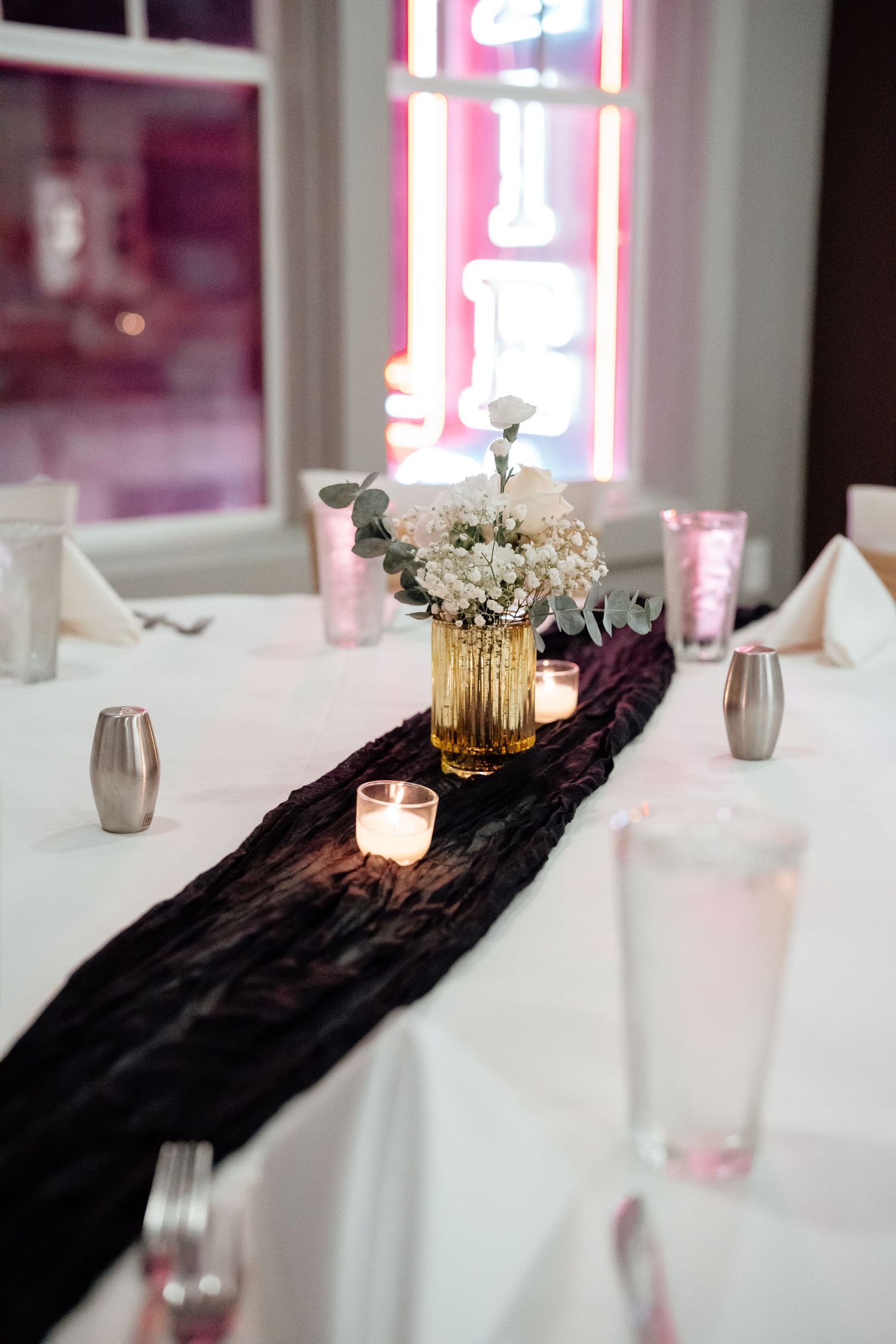 Elegant dining room setup with white tablecloths and decorative black runners for a formal event.