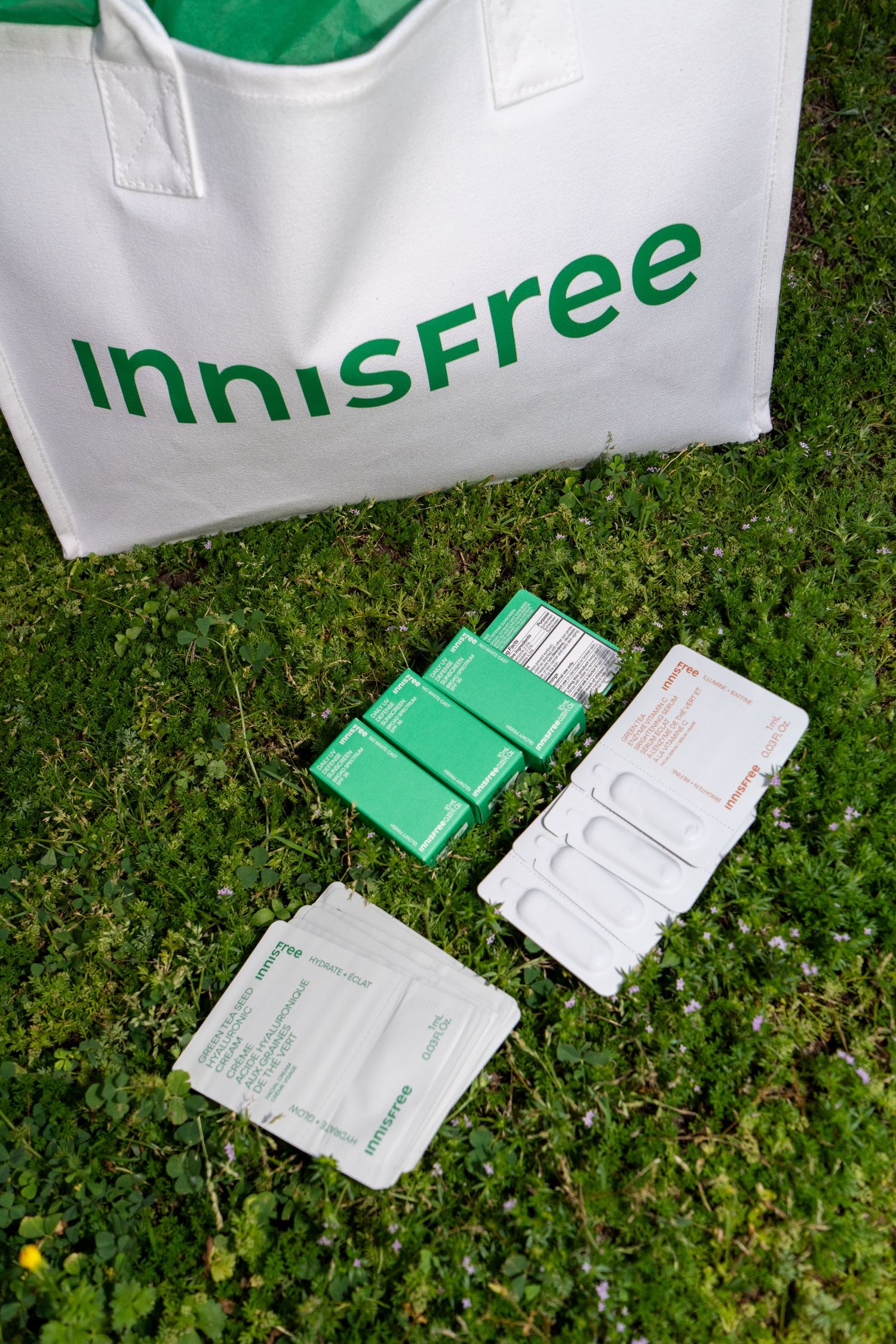 White bags and green promotional materials arranged on grass outdoors.