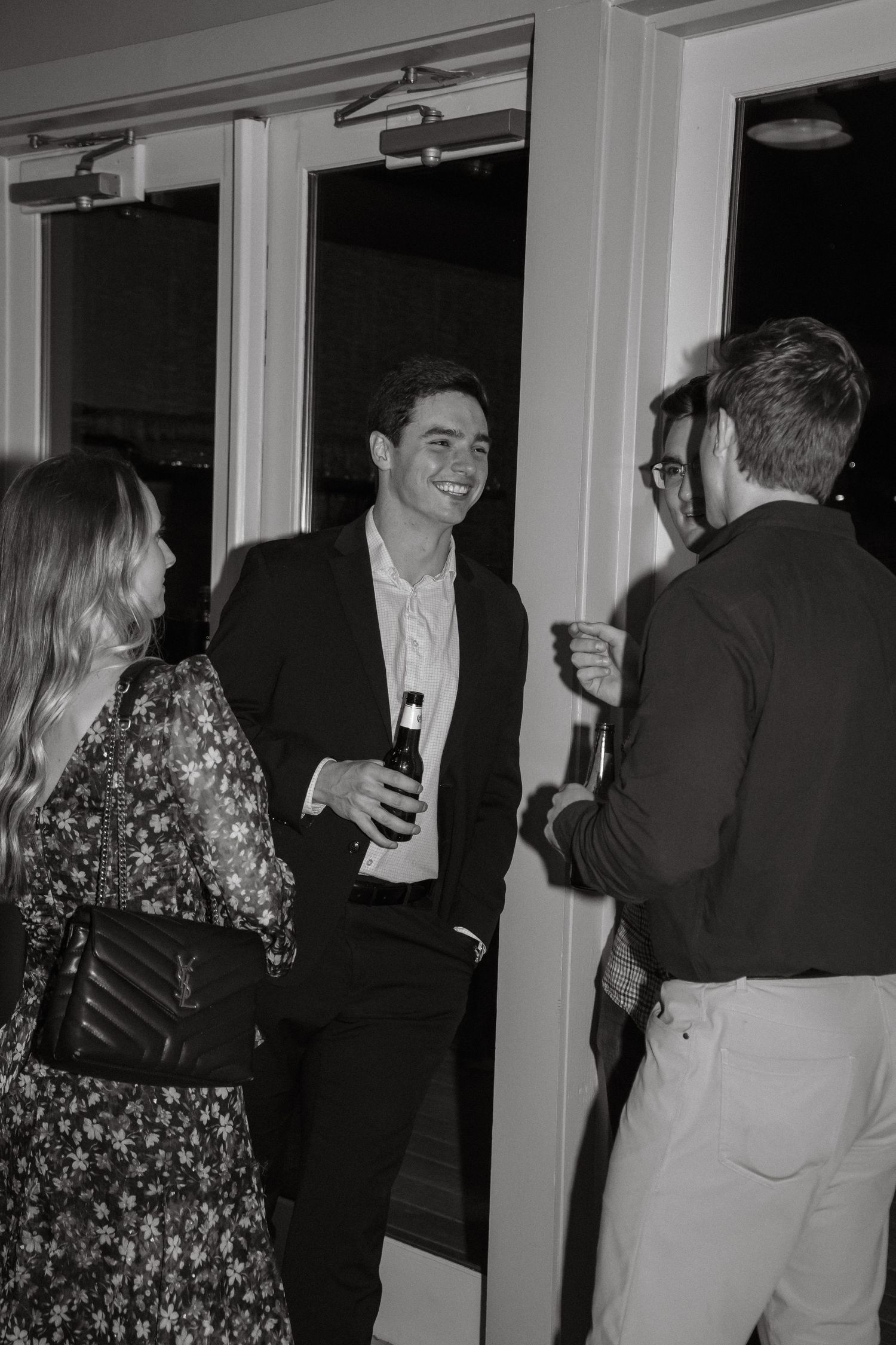 Guests gathered at an indoor event space mingle and socialize while holding drinks.
