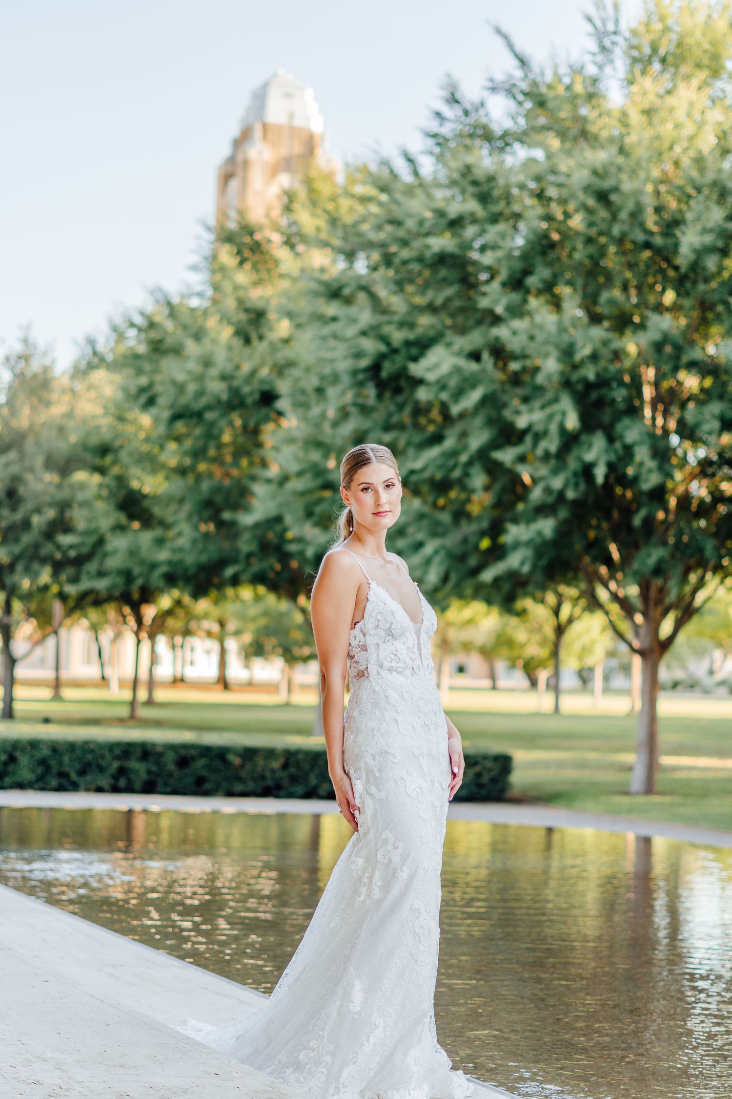 A stunning bridal portrait taken near a reflective pond with trees in the background.