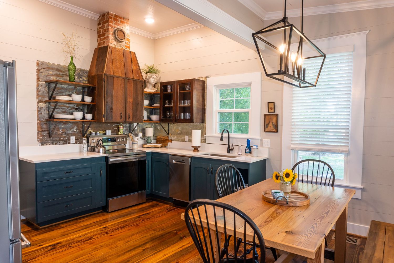 Modern farmhouse kitchen with white cabinets, wood accents, and vaulted ceiling design.