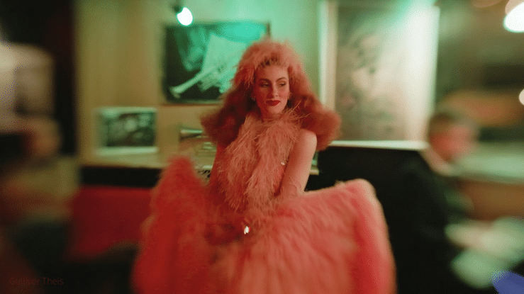 A person with bright red hair dances energetically in a dimly lit space creating a motion blur effect.