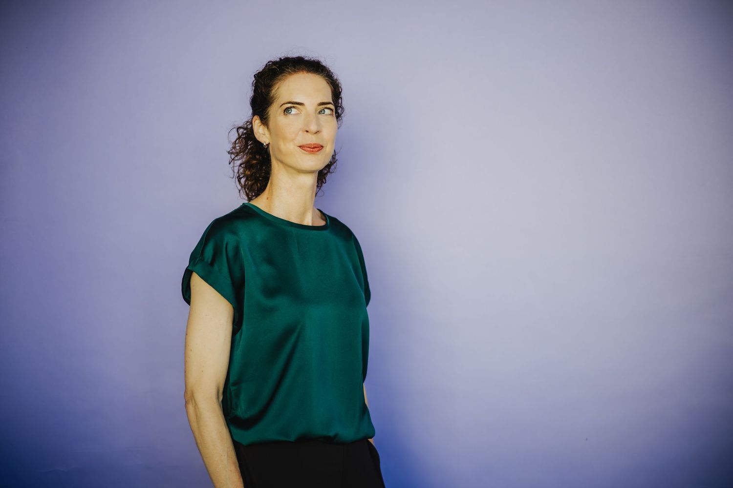 Professional portrait series against purple backdrop featuring emerald green attire.