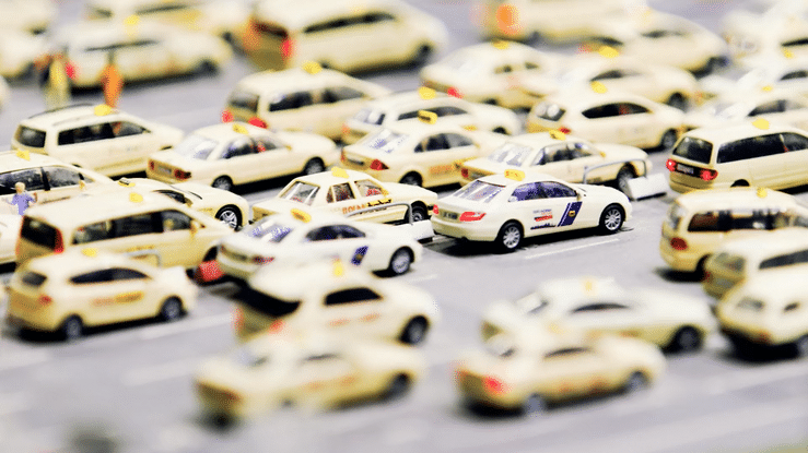 Miniature toy cars arranged in rows with a focus on yellow and white vintage model vehicles.