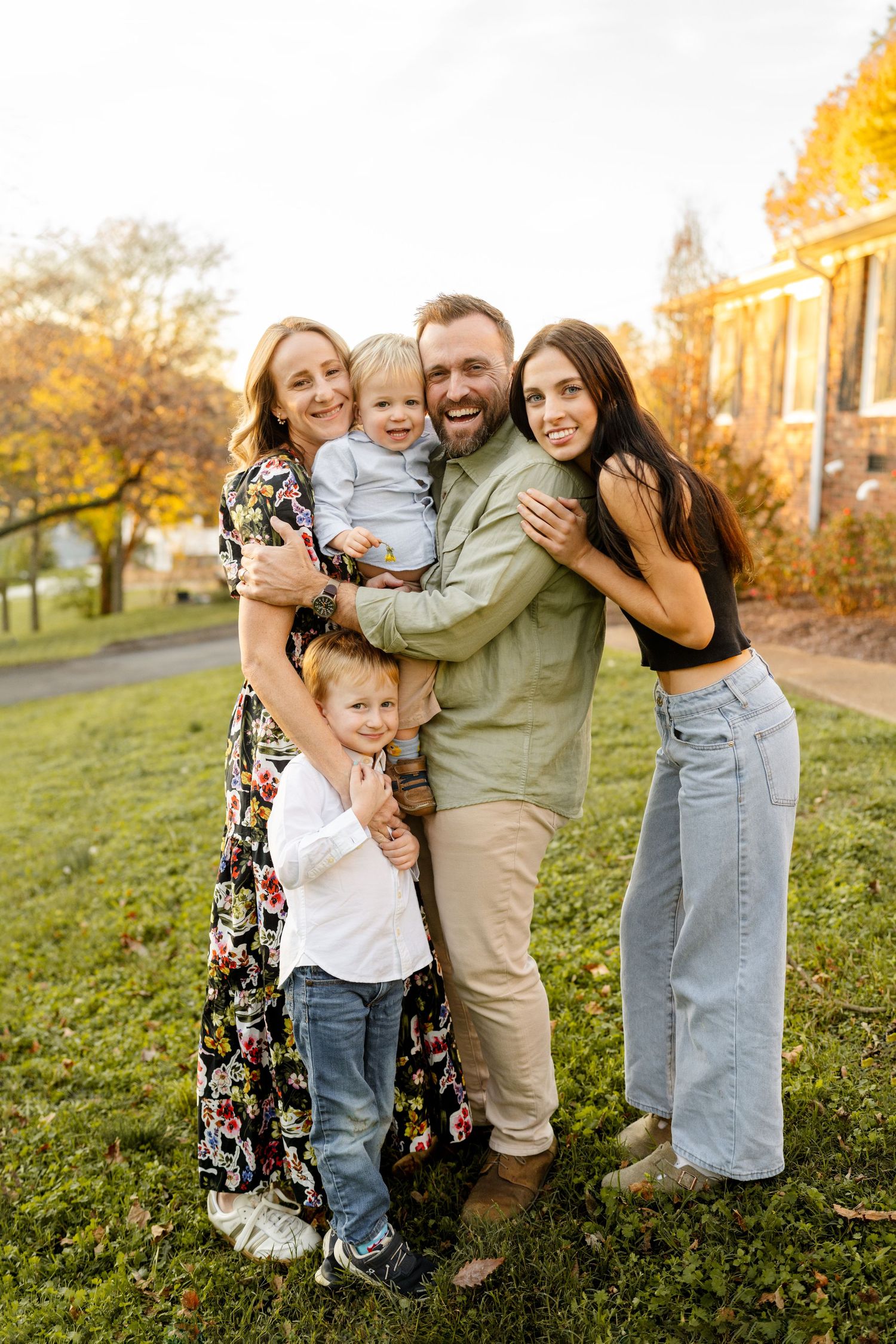 Happy family embracing outdoors during golden hour autumn photoshoot.