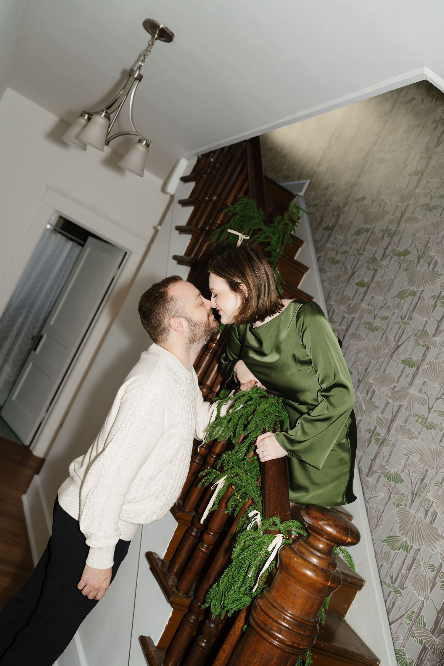 A person in a white shirt interacts with a large green plant in an indoor setting with a brick wall background.