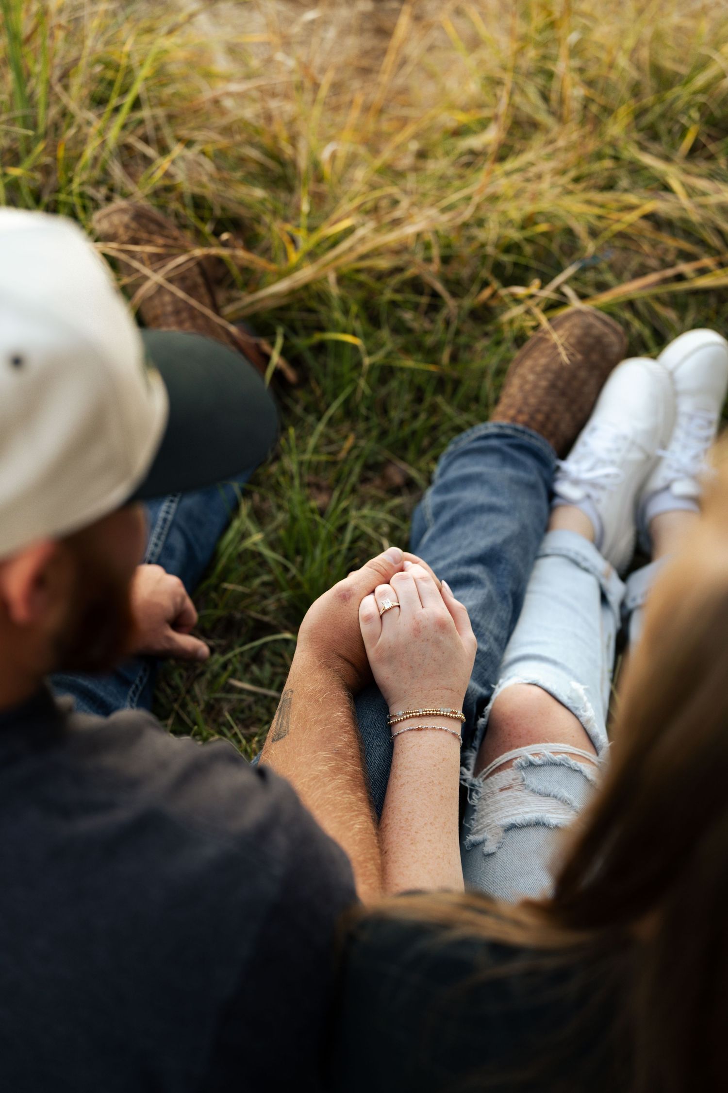 Close-up view of a engagement couple tall grass during a relaxed outdoor moment.