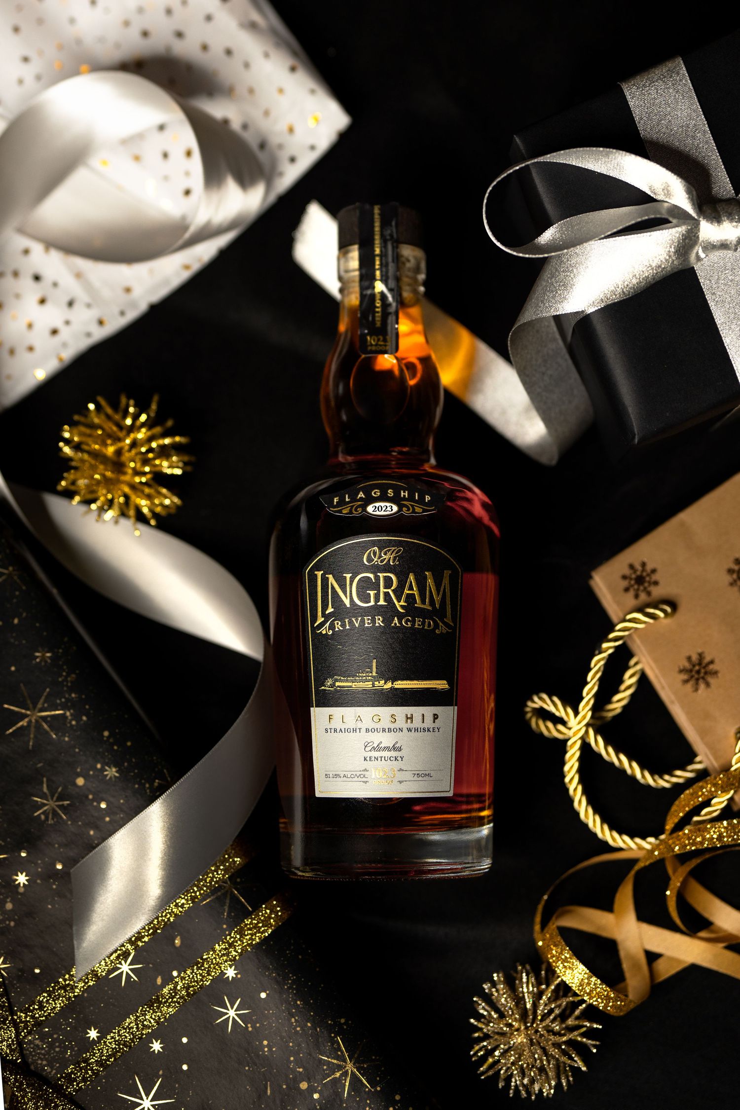 Elegant whiskey bottle with golden decorations and black ribbon on dark background with festive holiday accents.