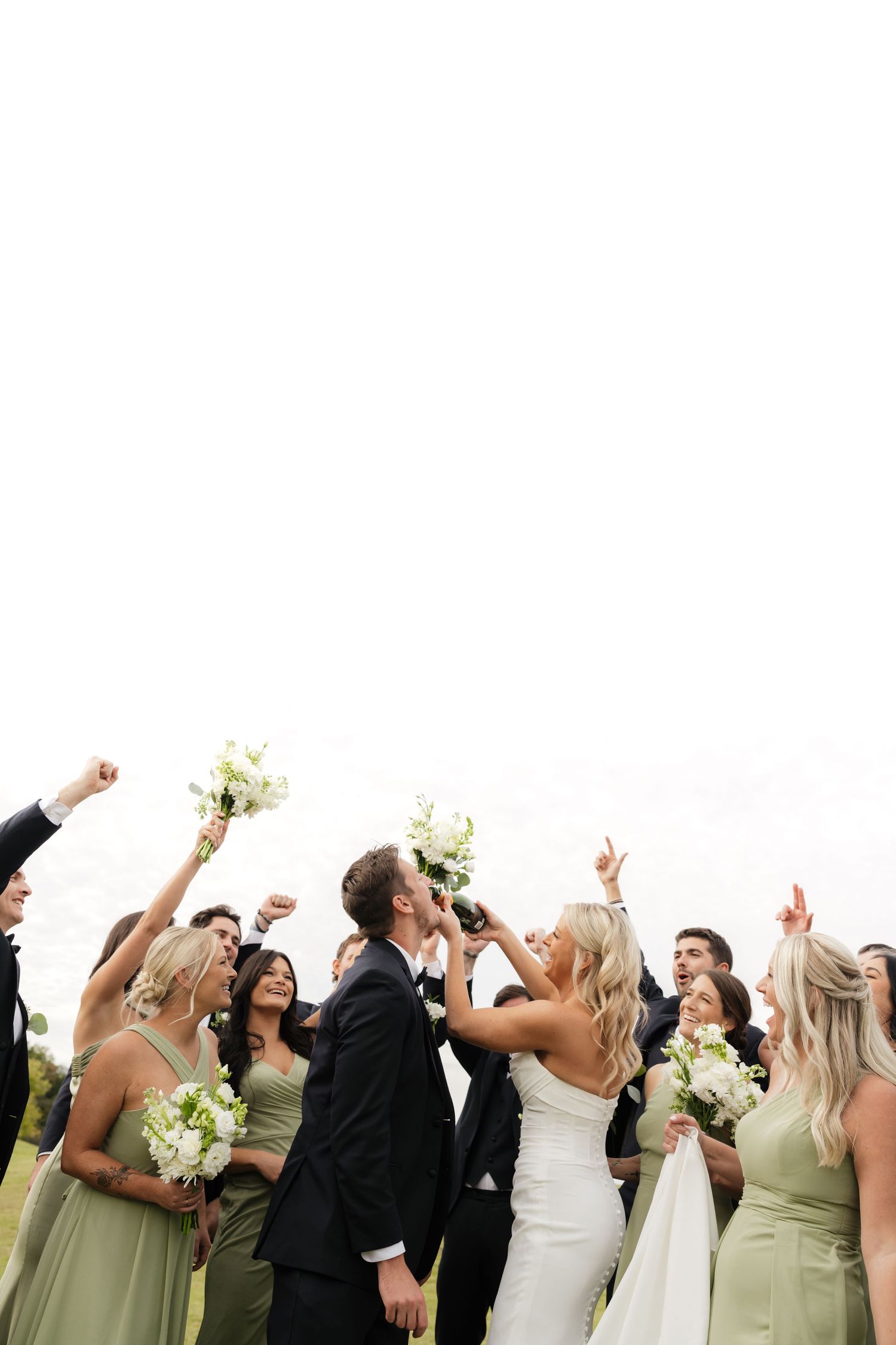 Wedding party in green dresses and dark suits celebrating with raised arms outdoors at Gaylord Golf Links in Nashville Tennessee.