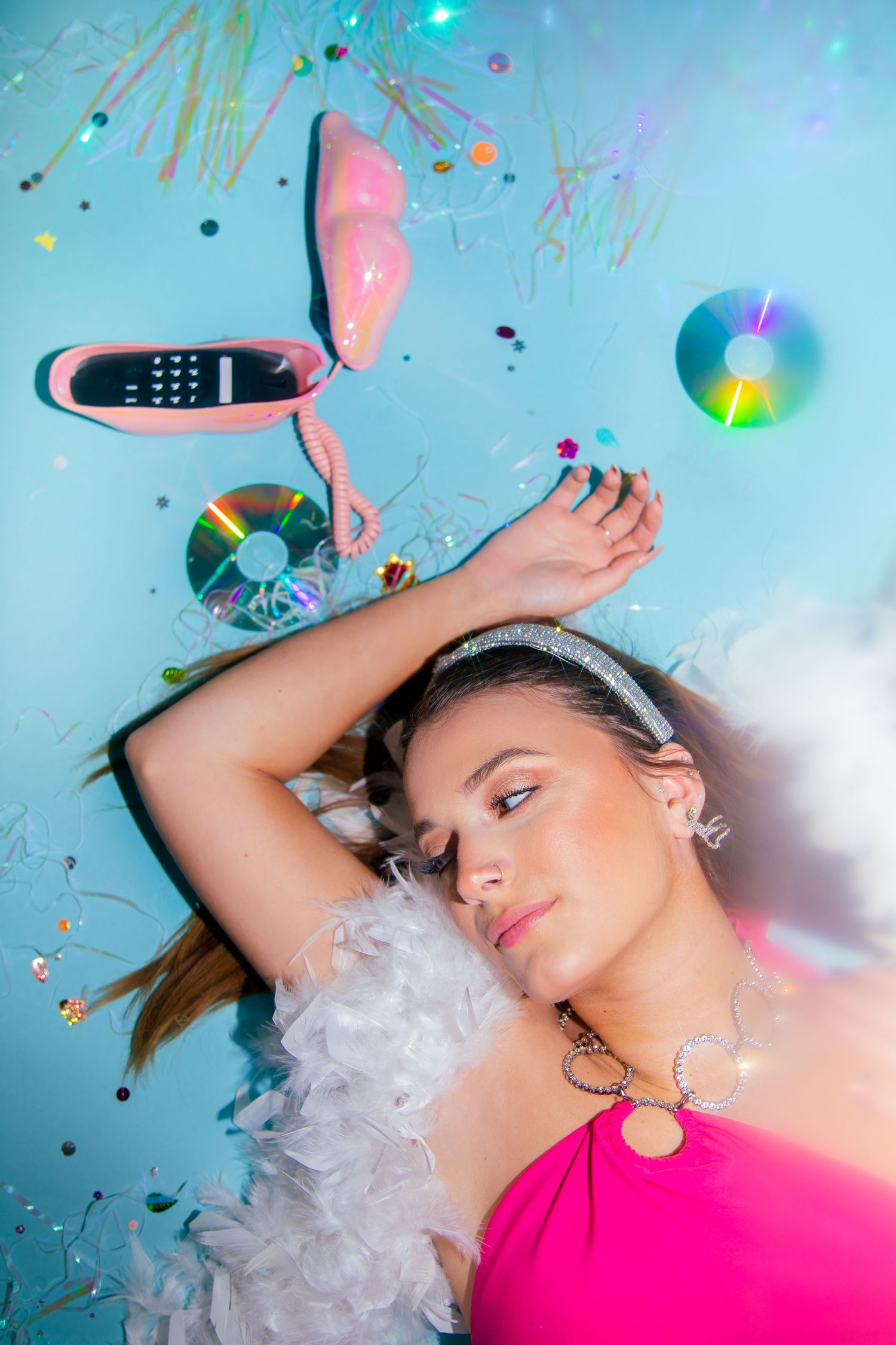 Artistic portrait with confetti and props against blue background with dreamy lighting effects.