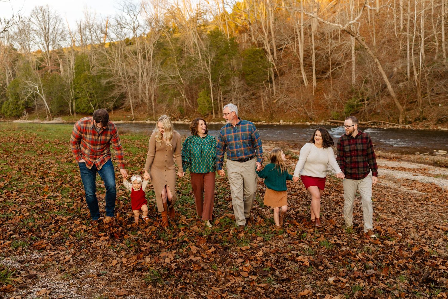 Fall family portrait with group lined up against autumn trees and fallen leaves.