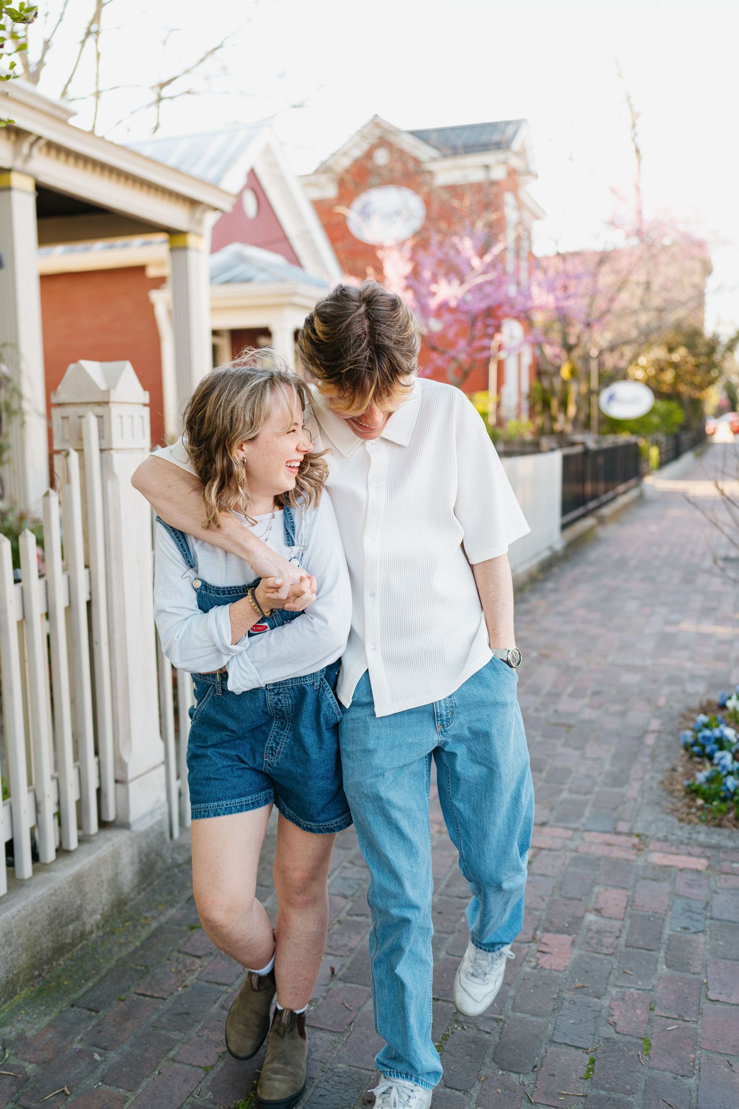 Playful candid moment captured on a brick pathway with white picket fence background.