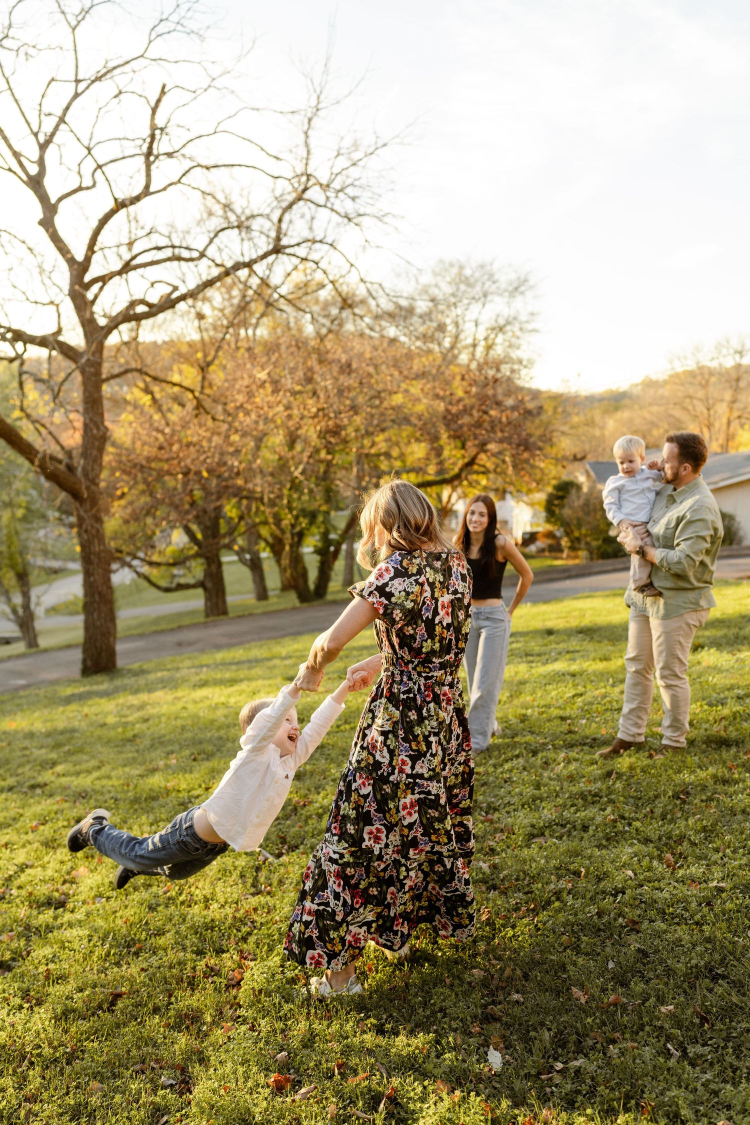 Family playing and having fun in orchard during golden hour.