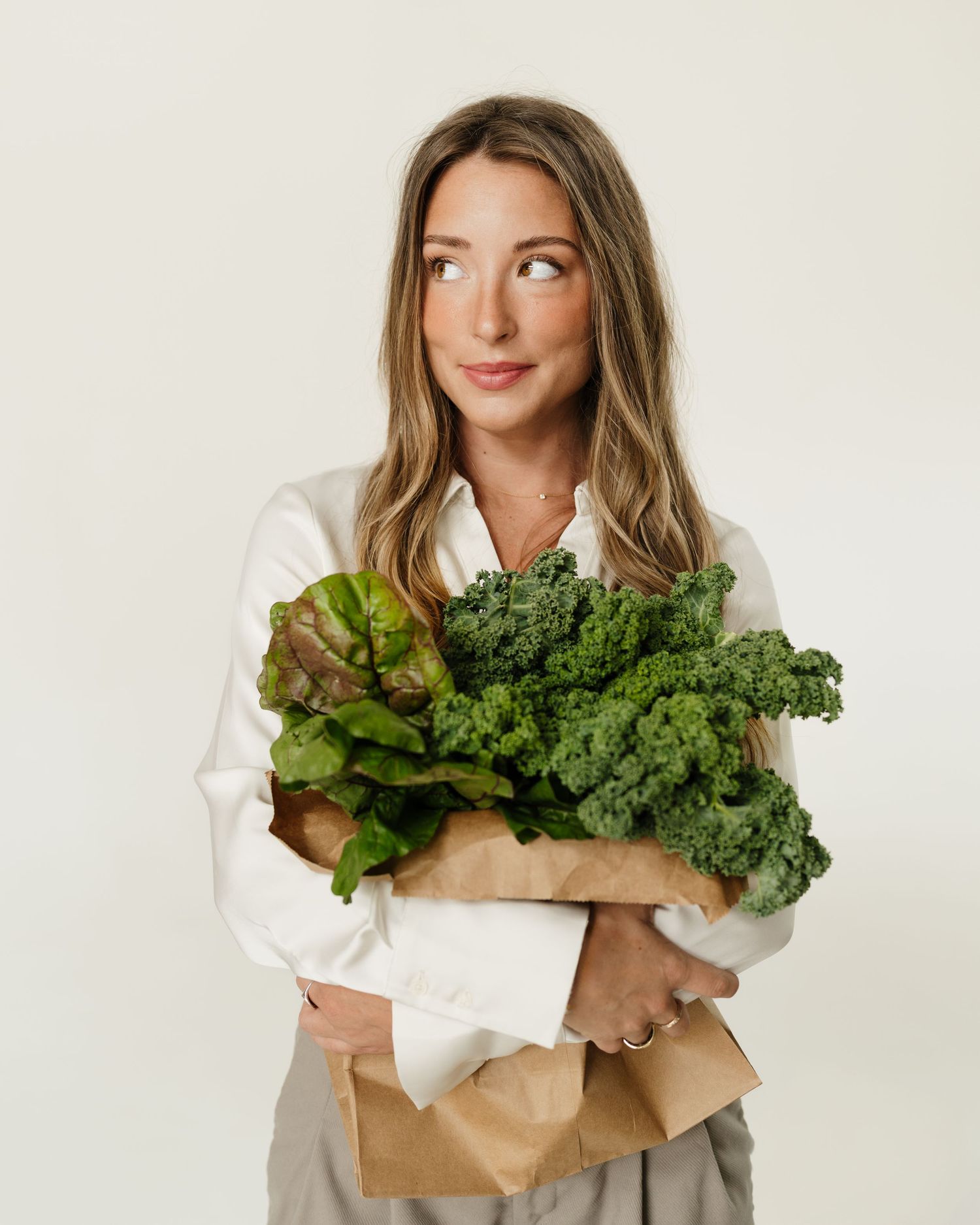 Branding photos featuring fresh leafy greens and kale held in brown paper shopping bag for Nutrition by Emma, Nashville dietician.