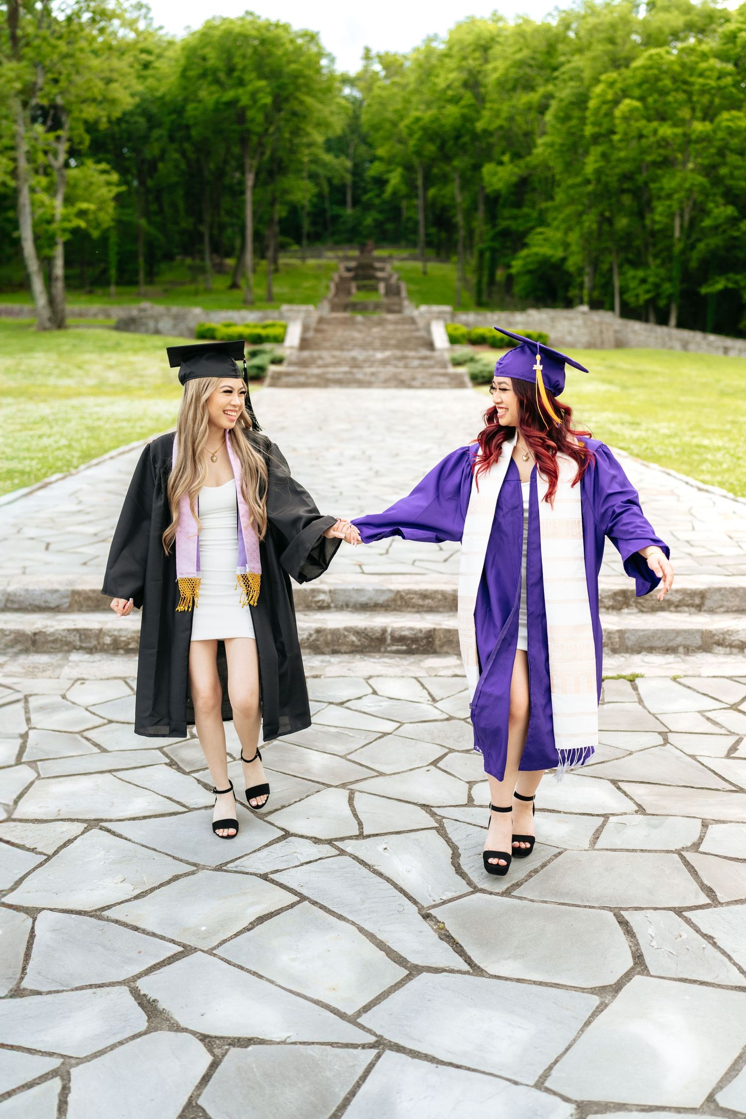 Graduation photoshoot featuring contrasting purple and black academic regalia on stone pavement.