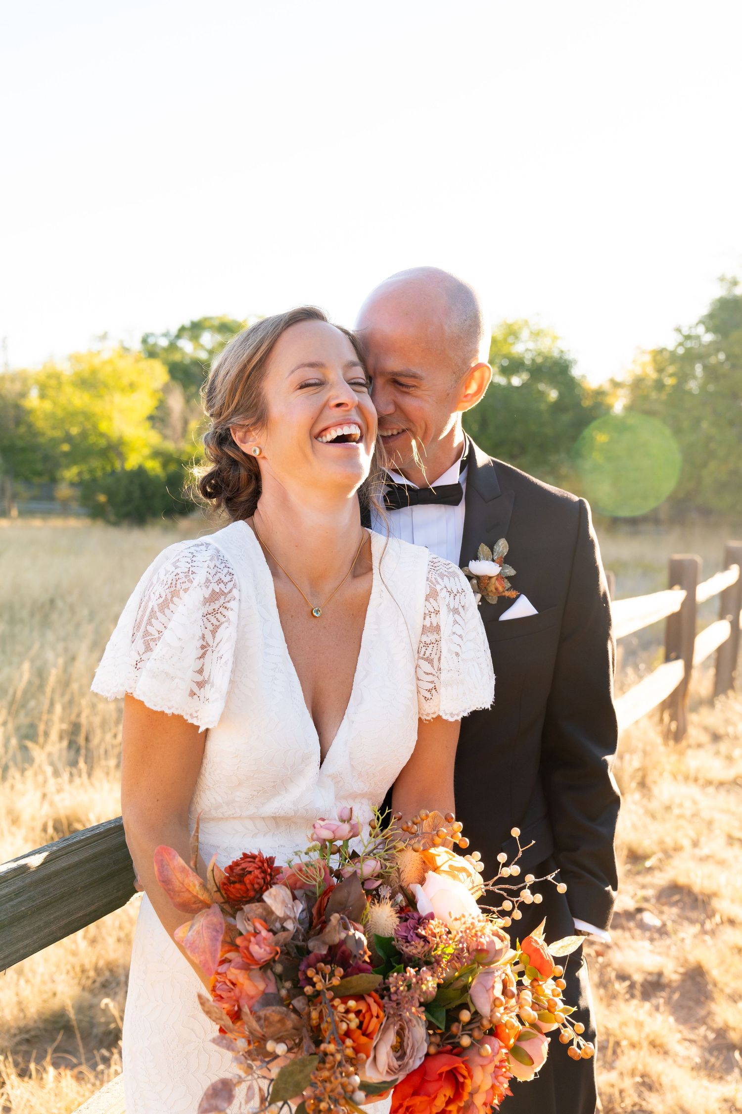 Couple shares intimate moment with autumn-colored bouquet in golden sunset light.