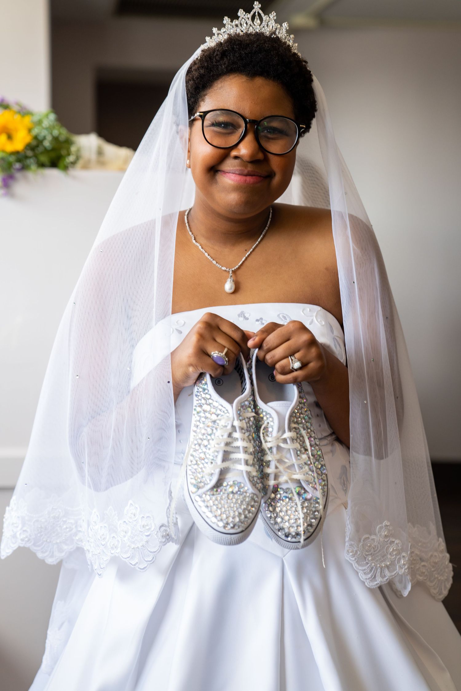 Wedding day details featuring a tiara, white studded sneakers, and a bride in a flowing white dress with delicate lace veil.
