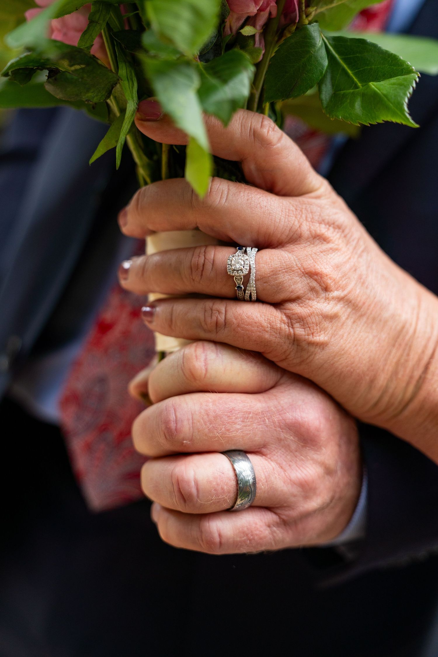Close-up shots of hands holding flowers and displaying wedding rings.
