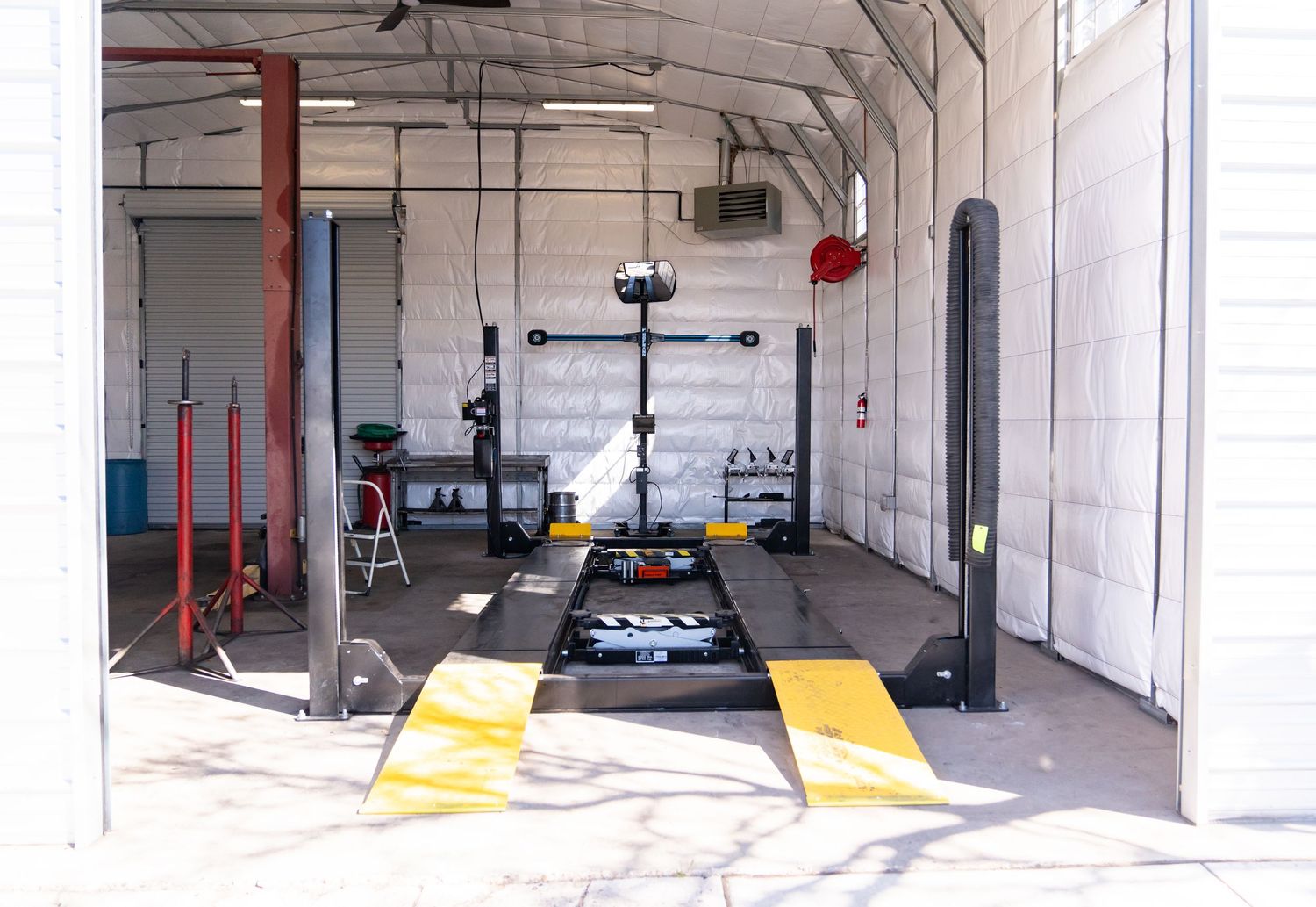 Wide panoramic view of an empty automotive service center with white walls and red support columns.