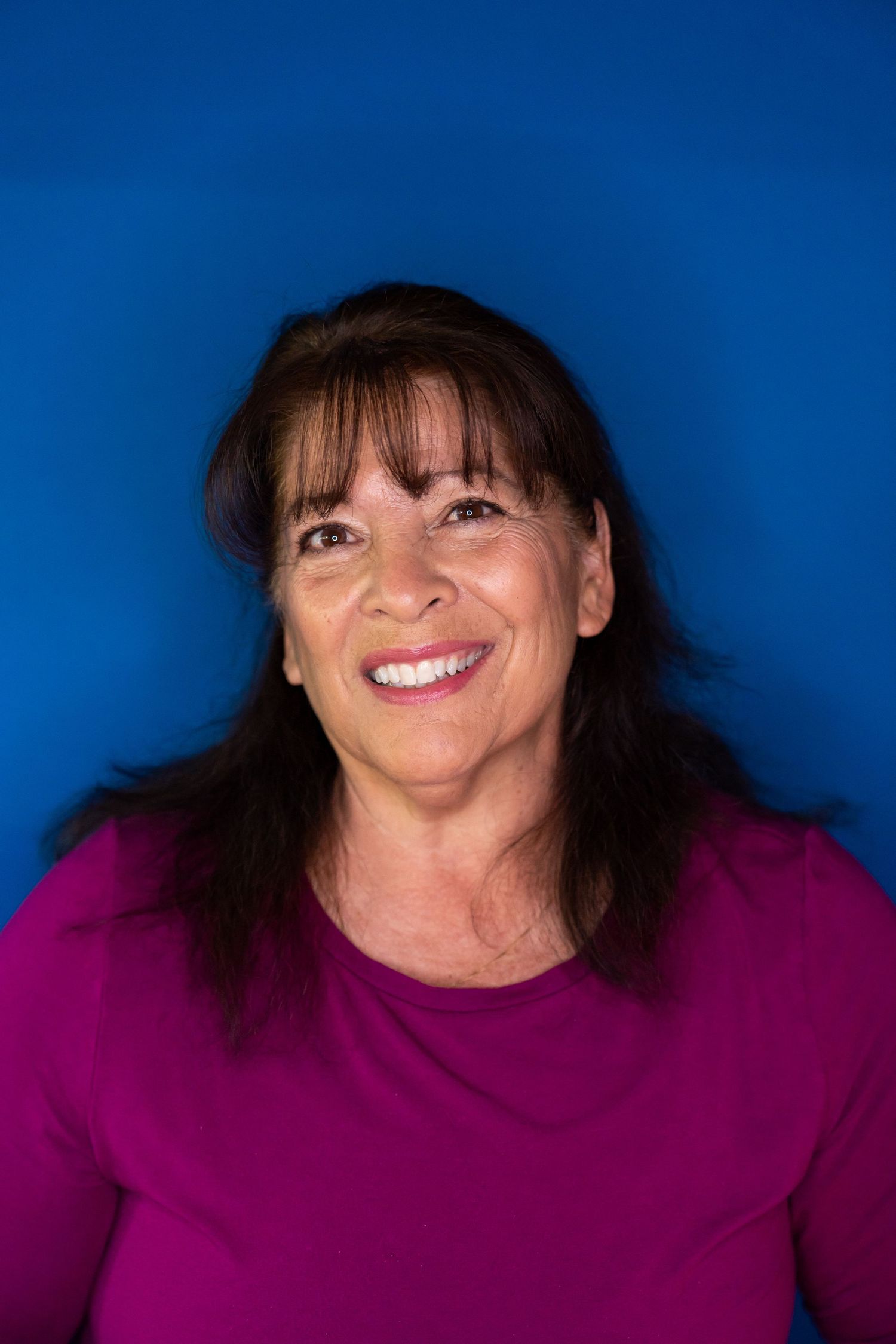 Person in magenta sweater poses against bright blue studio background.