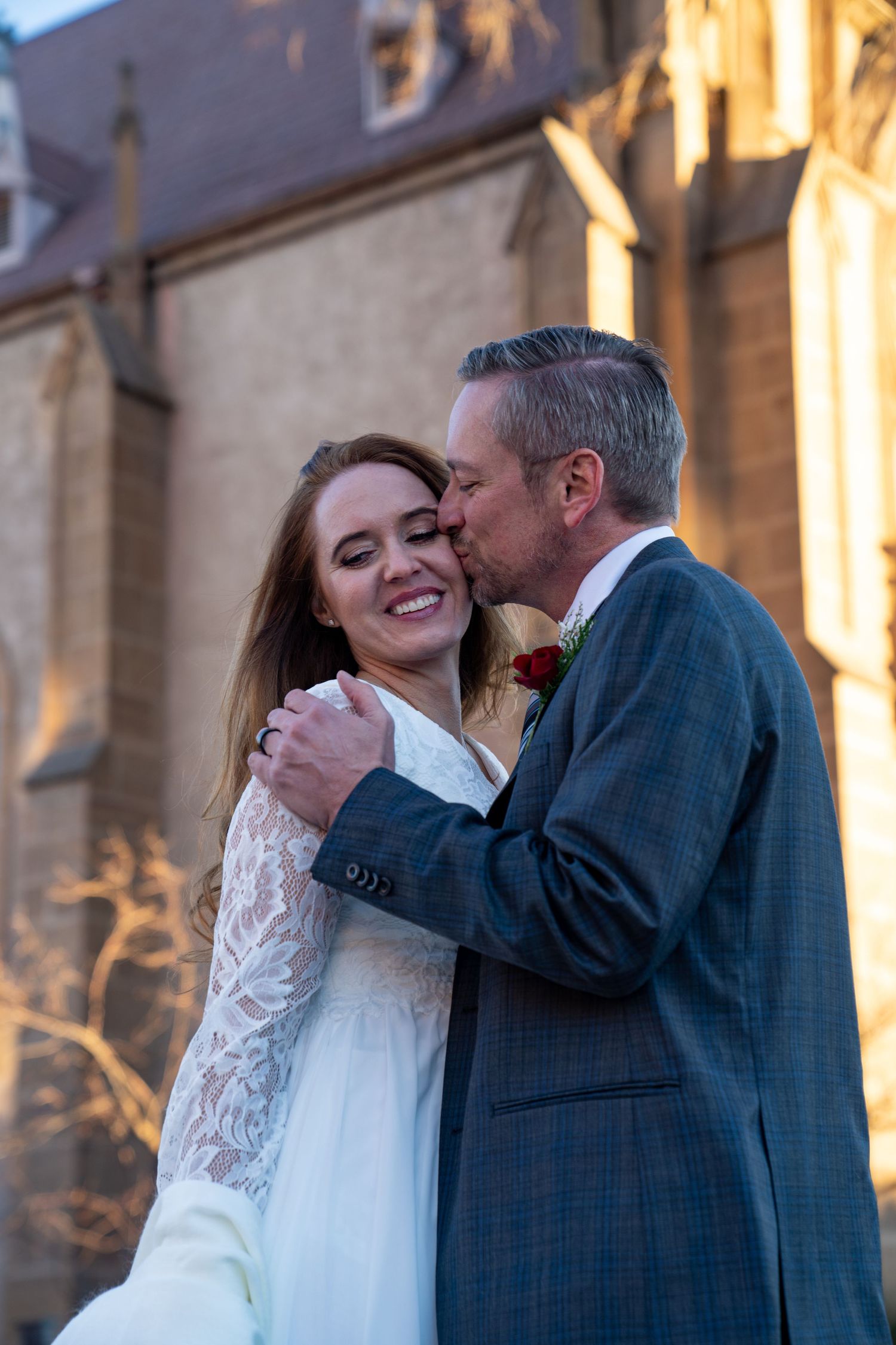A romantic winter wedding portrait in front of a historic church during golden hour.