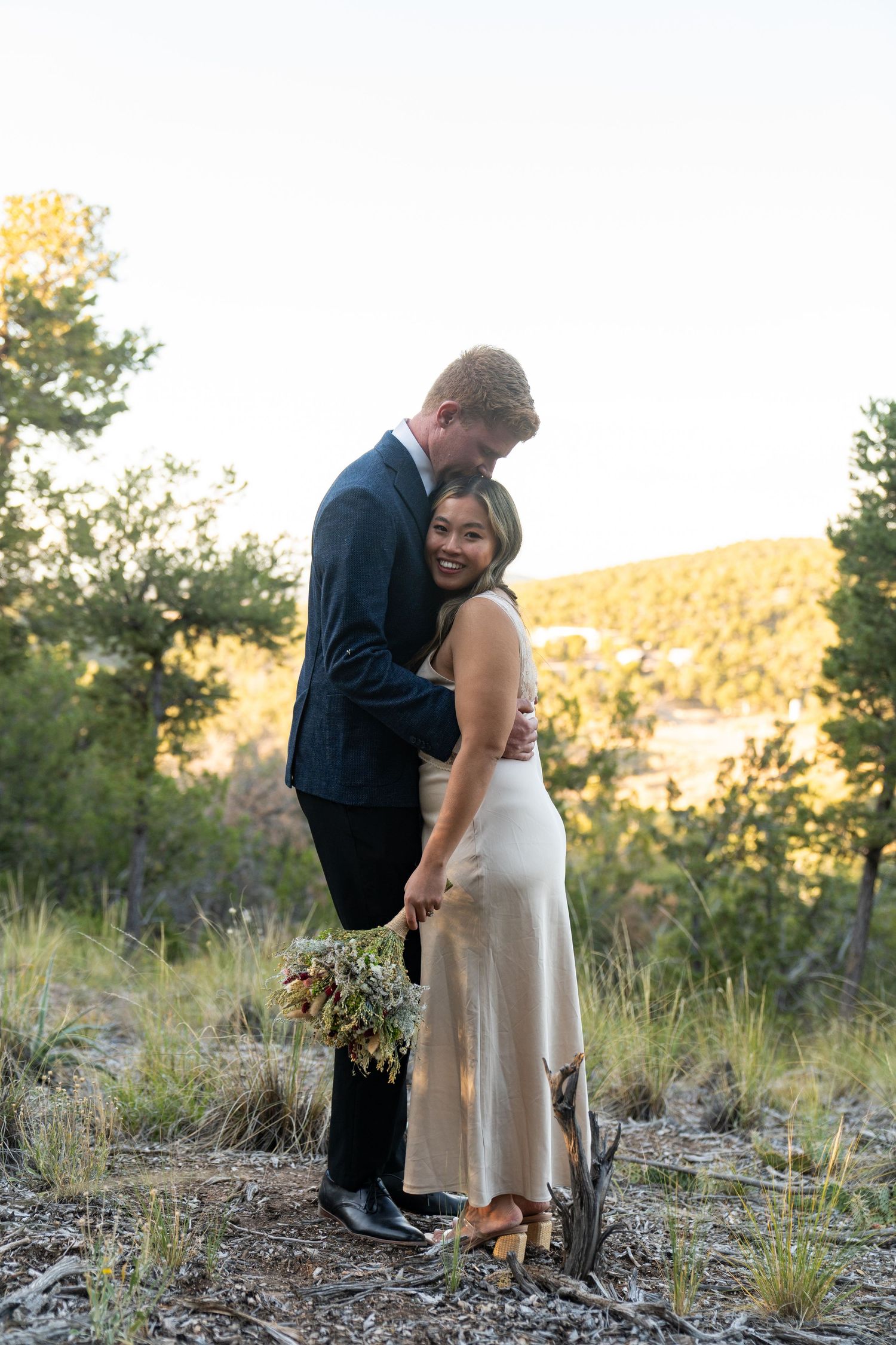 Couple sharing intimate moment during sunset photoshoot in mountain landscape.