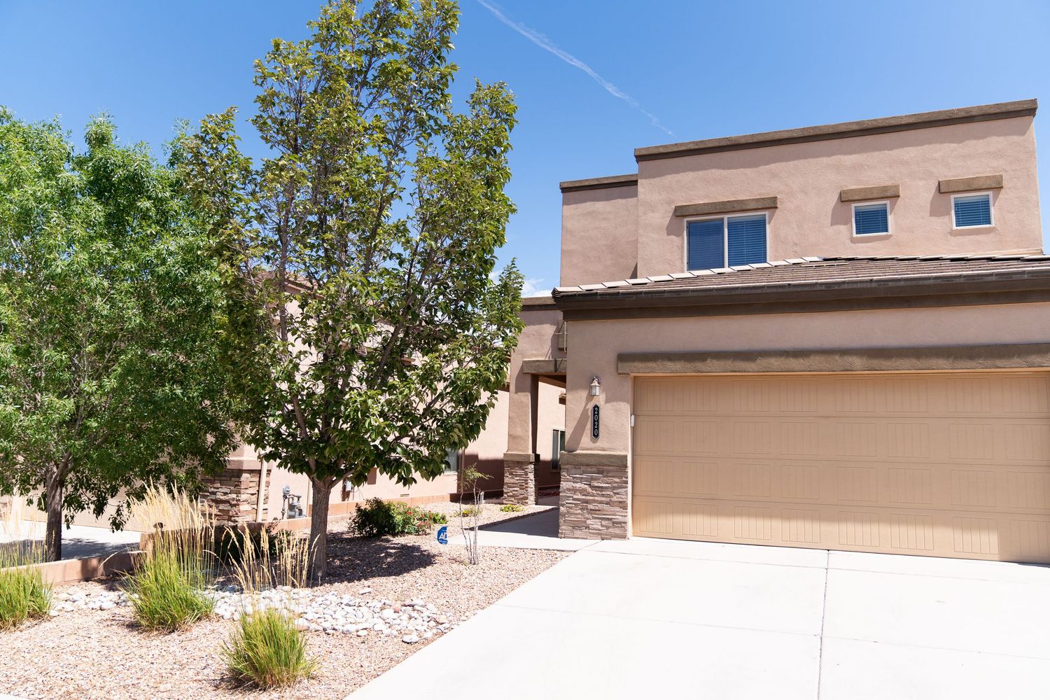 A series of modern stucco homes with desert landscaping and rock features in a southwestern residential neighborhood.