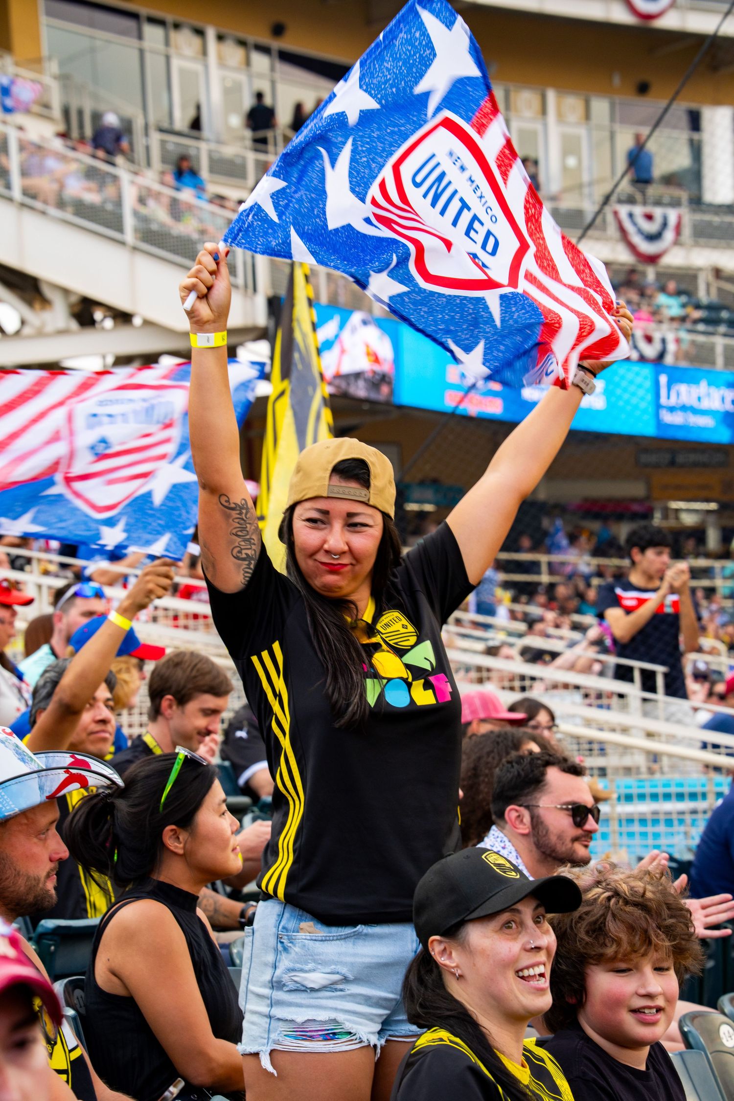 Minnesota United FC fan waves team flag enthusiastically at an MLS soccer match in a packed stadium.