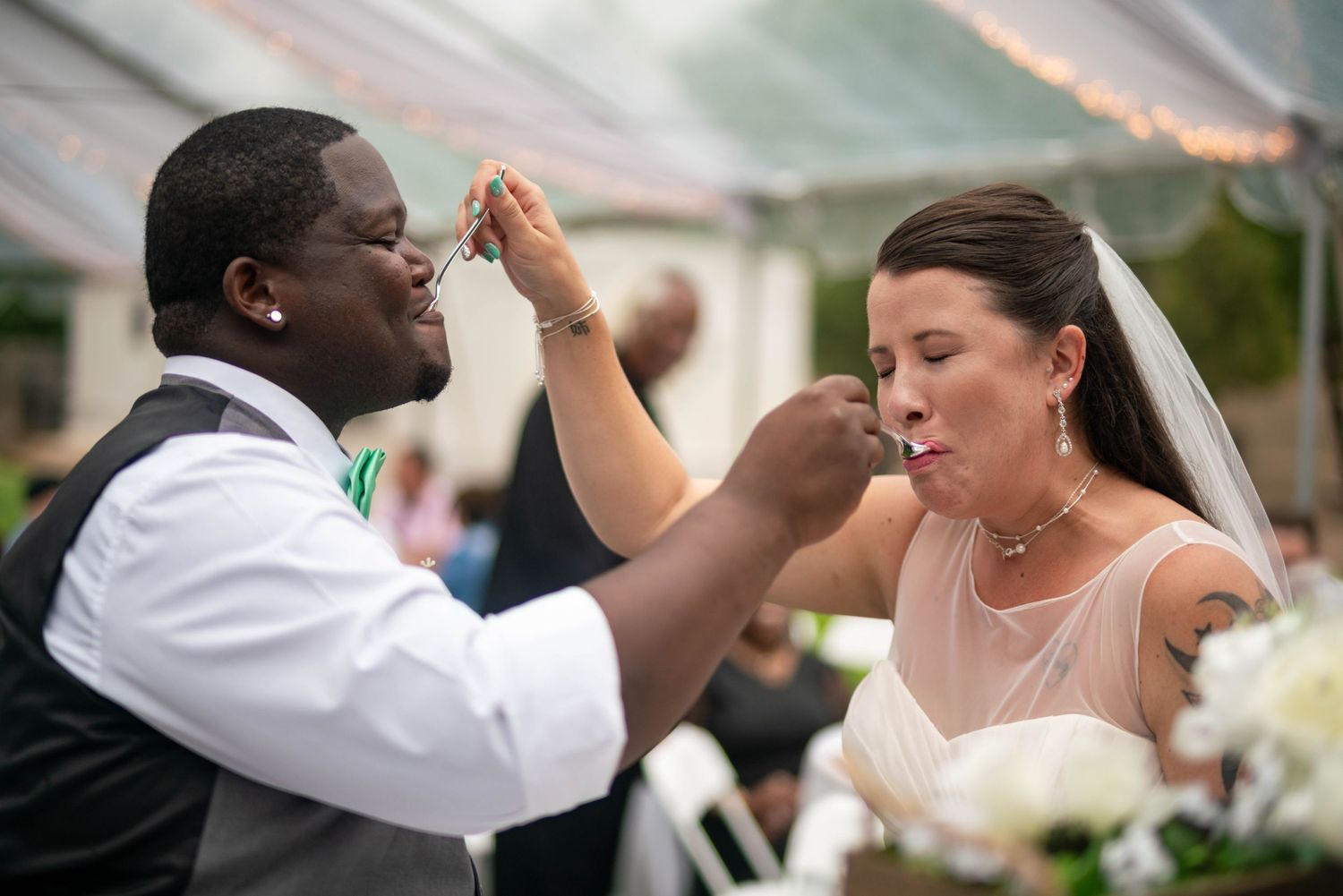A couple dances together at a wedding reception with joyful expressions and elegant attire.