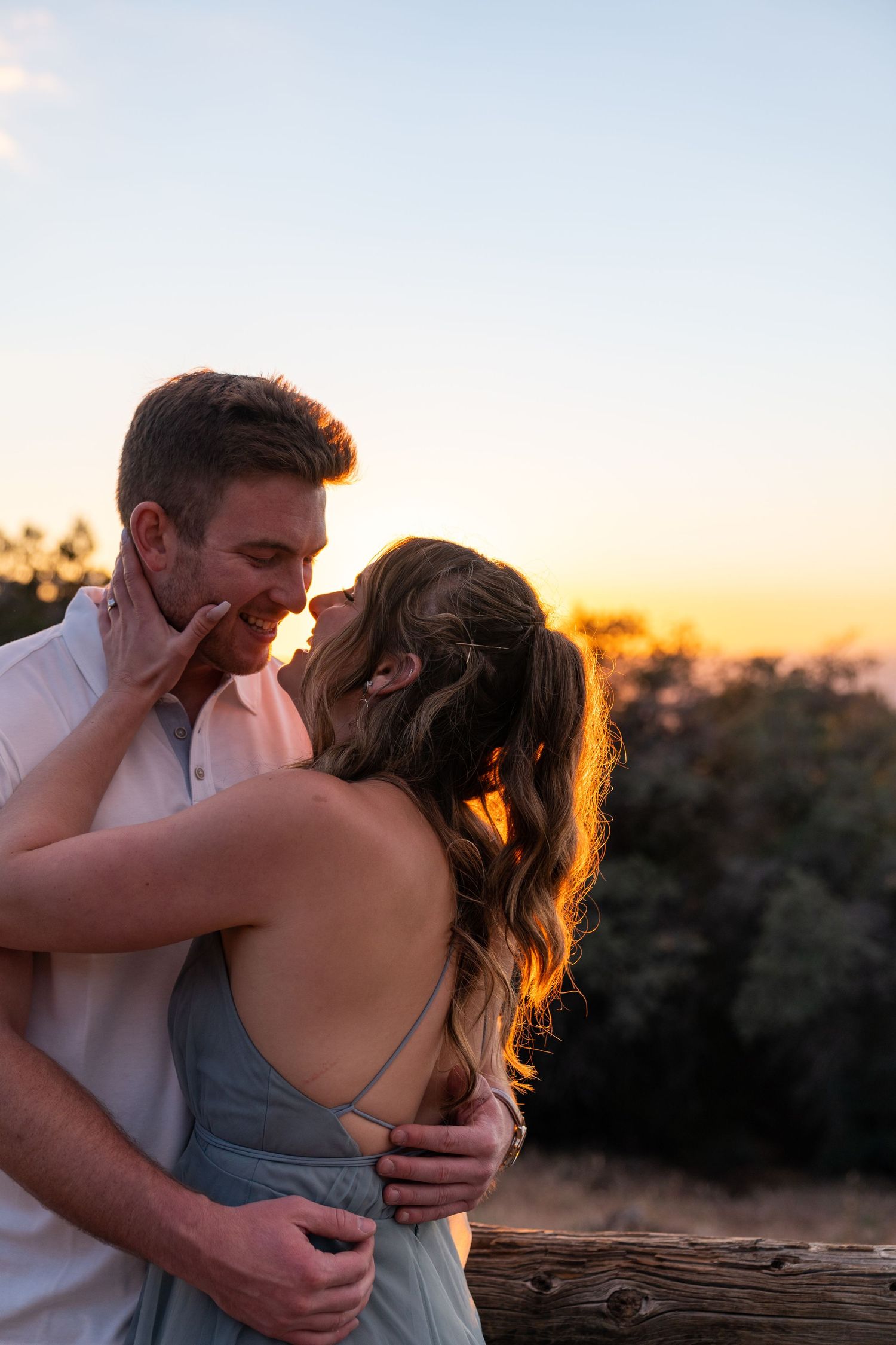 Intimate sunset portrait of couple embracing against golden sky.