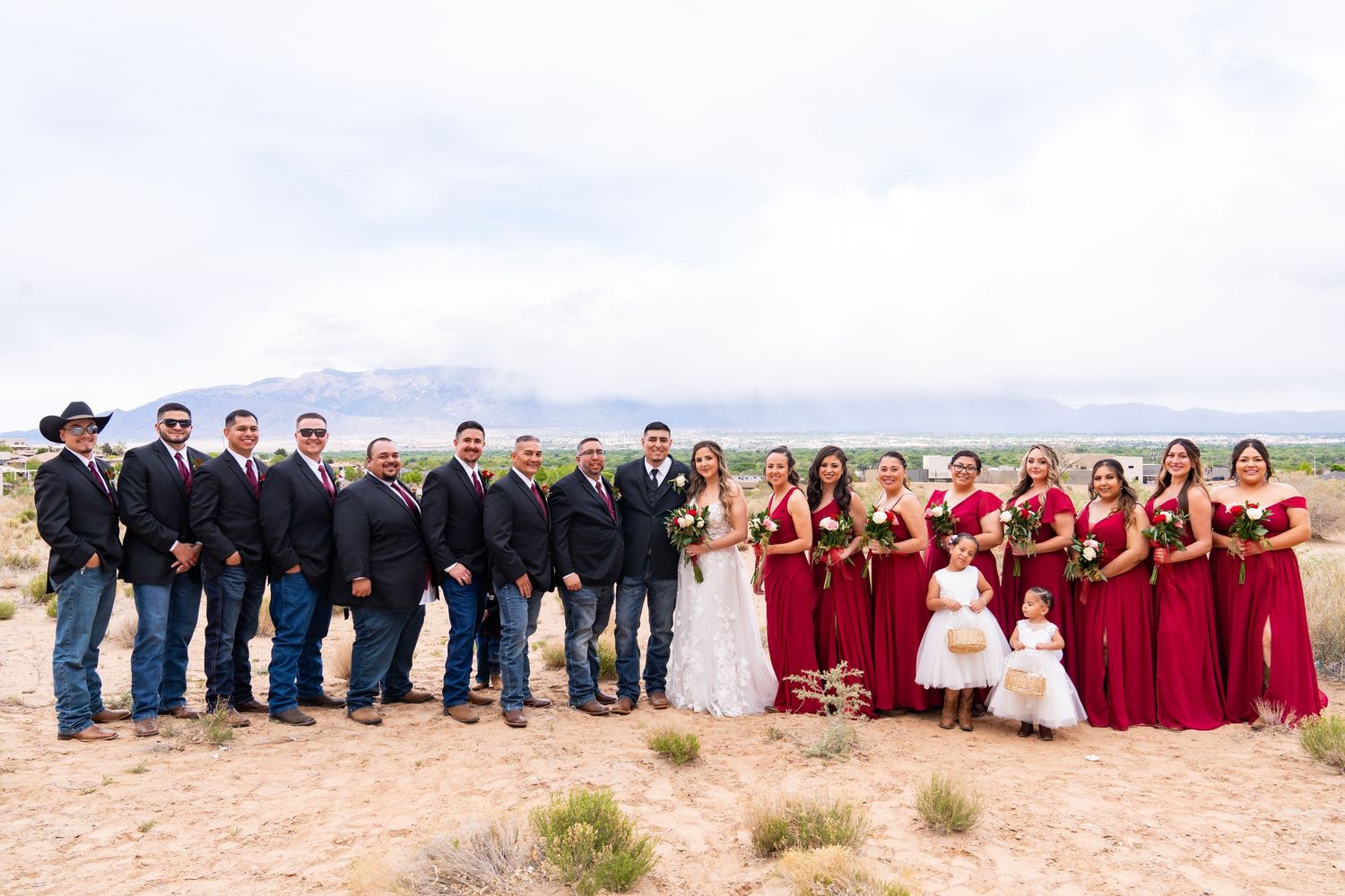 Full wedding party lineup photographed outdoors against a natural landscape.