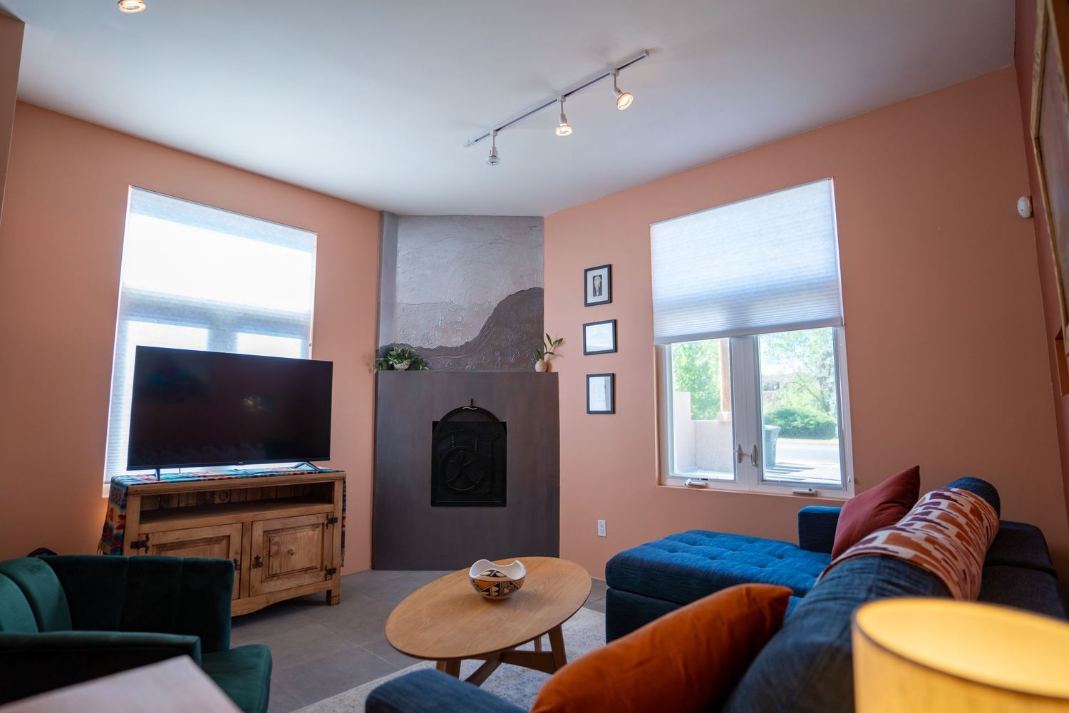 Modern living room with salmon-colored walls, track lighting, and mounted TV displays a minimalist contemporary design.