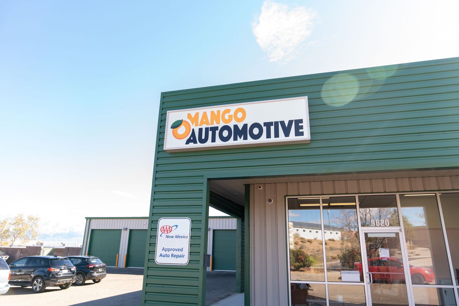 An exterior view of a green commercial building with automotive and NAPA signs mounted on the facade.