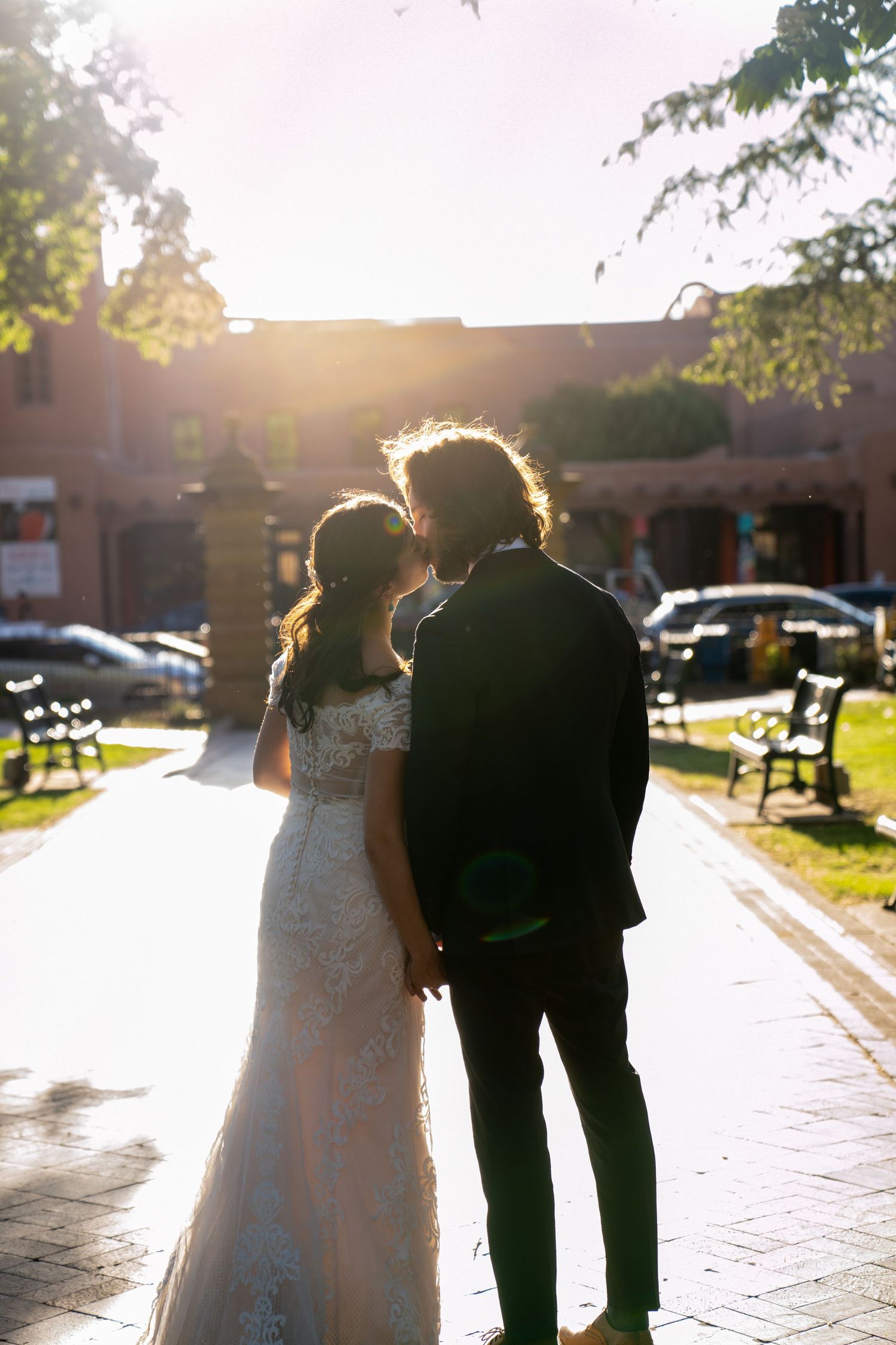 A couple walking together at sunset casting long shadows on a paved walkway.